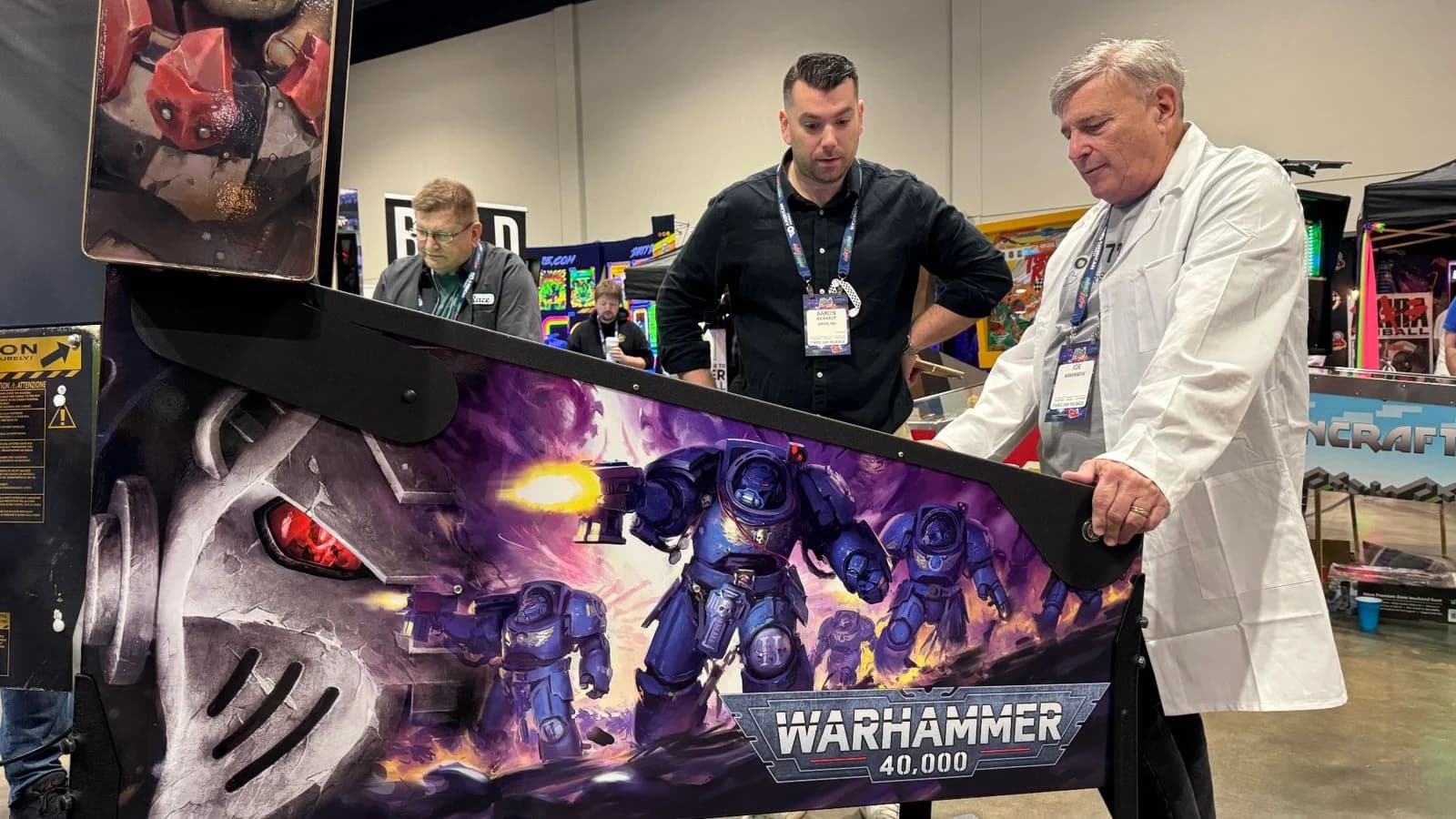 A Warhammer 40,000 homebrew pinball machine with three people standing behind it
