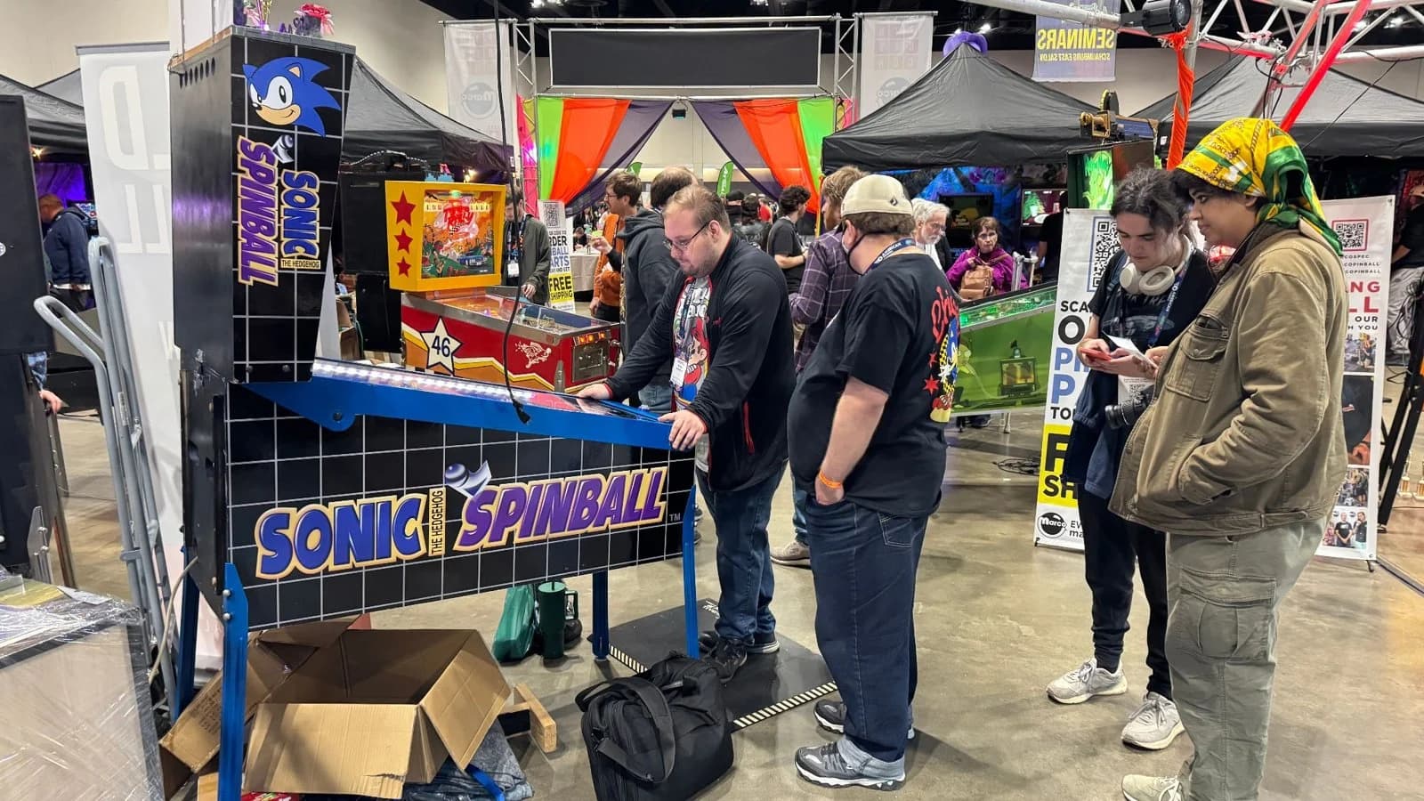 A Sonic Spinball pinball machine with players around it