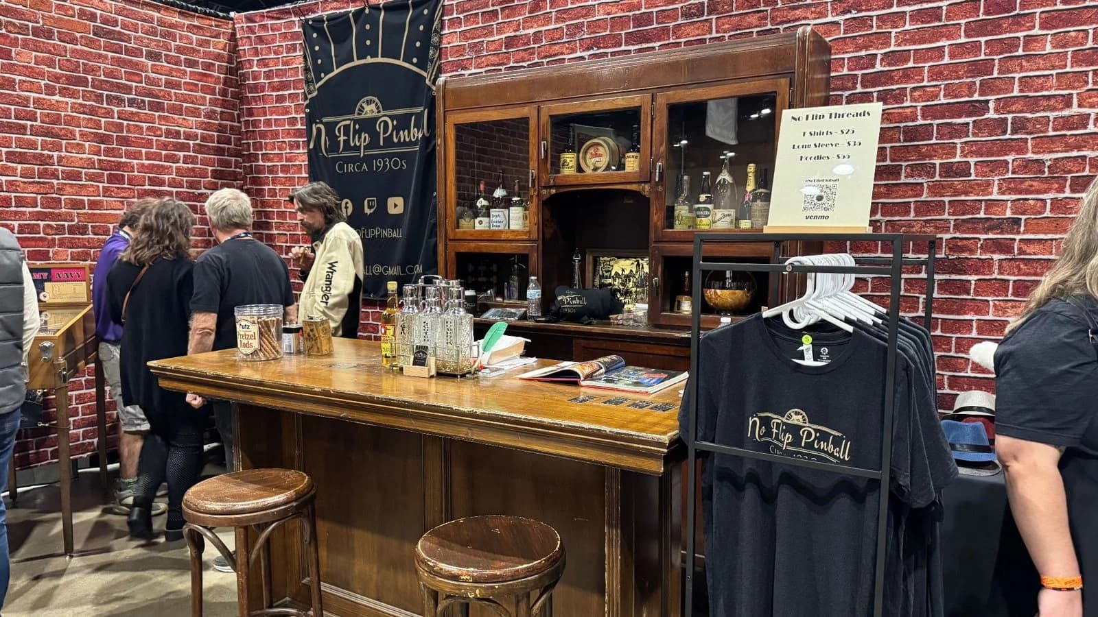 The No Flip Pinball booth, set up as a bar with stools and shirts for sale