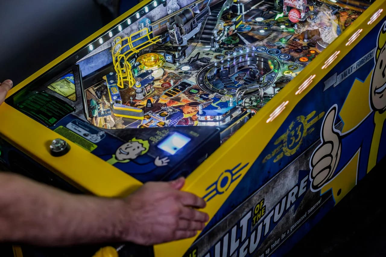 The Fallout Limited Edition playfield from the side, the vault lower playfield lit, The Vault of the Future cabinet art below