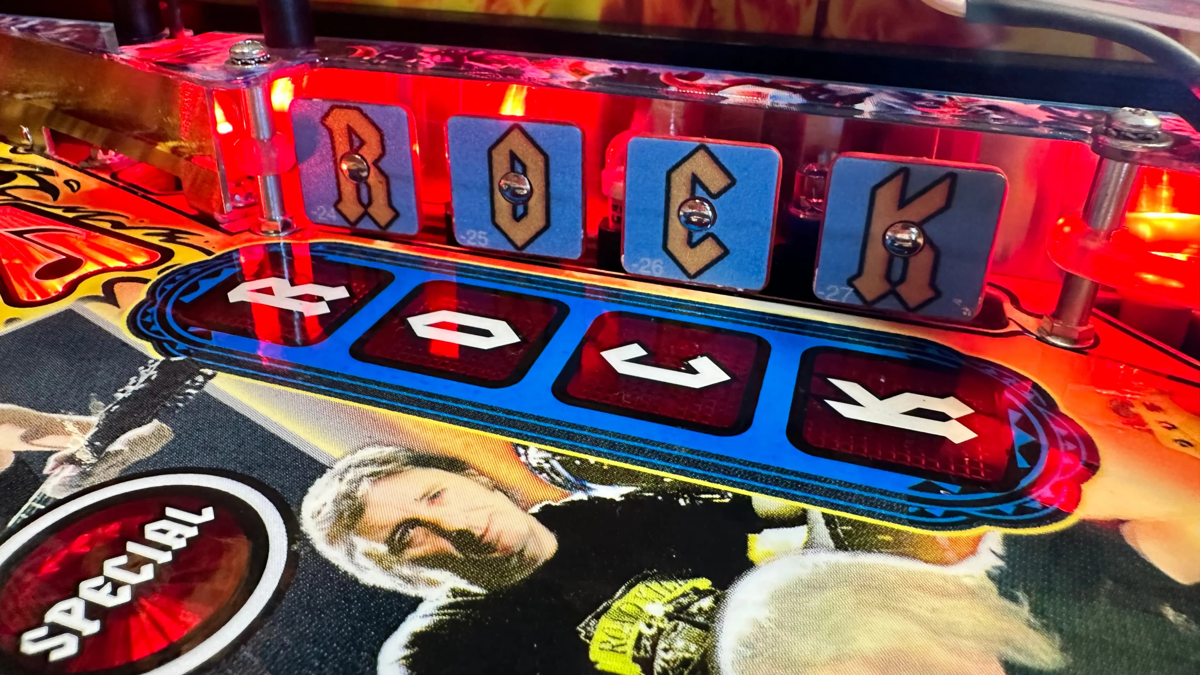 Pinball machine display with colorful letters and illuminated red buttons
