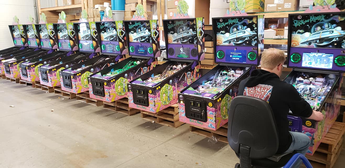 Multiple Rick and Morty-themed pinball machines lined up in a warehouse