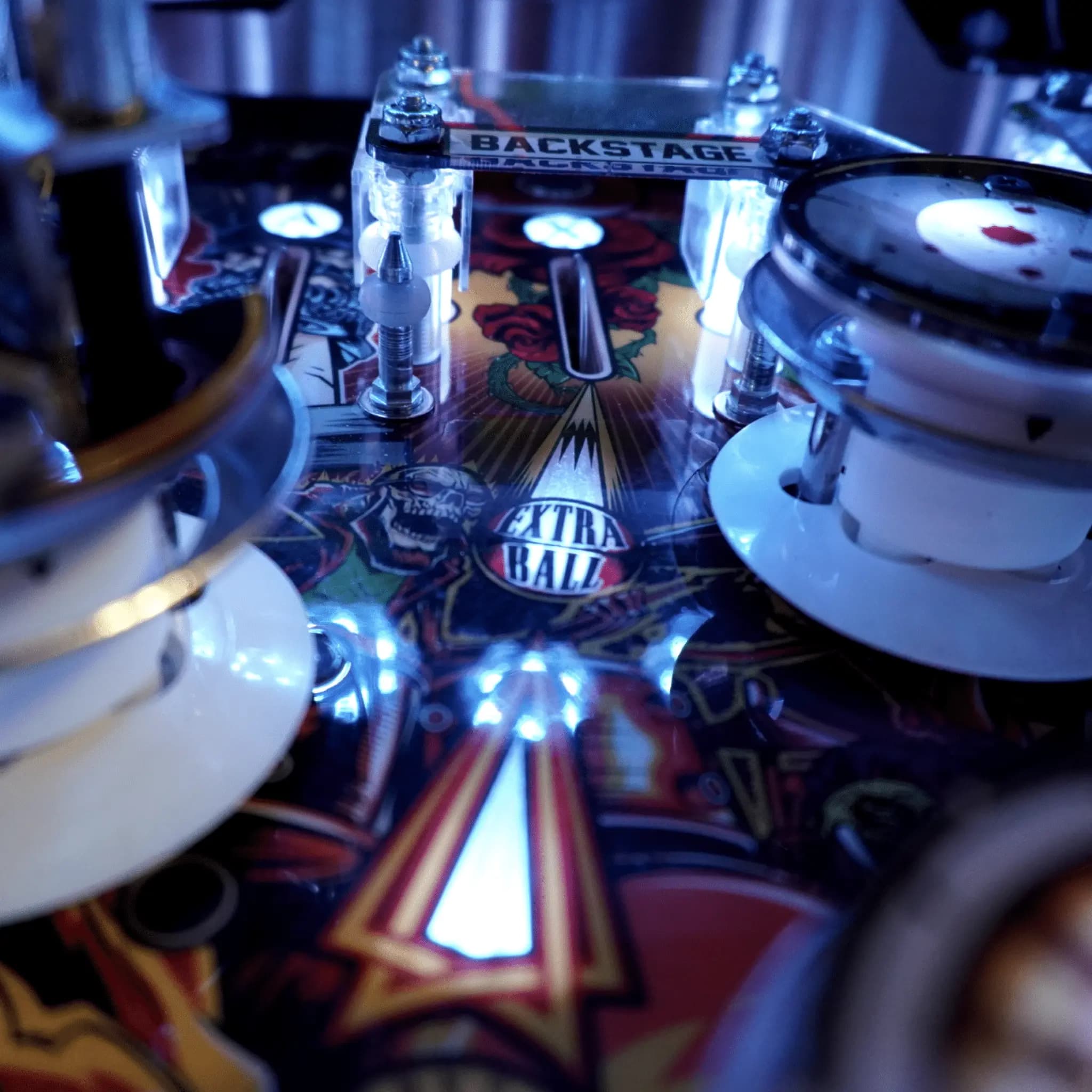 Pinball machine close-up with blue-tinted lights and backstage sign
