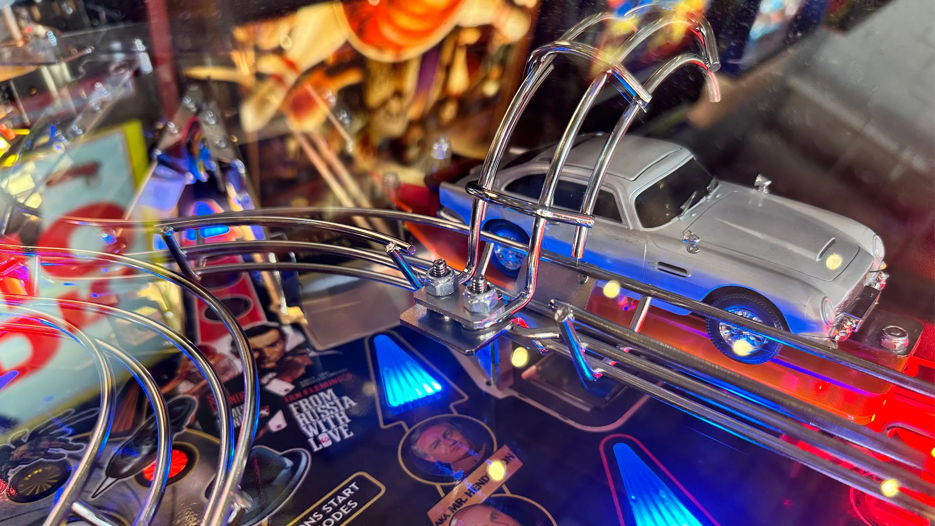 Colorful pinball machine with silver car and curved metal tracks