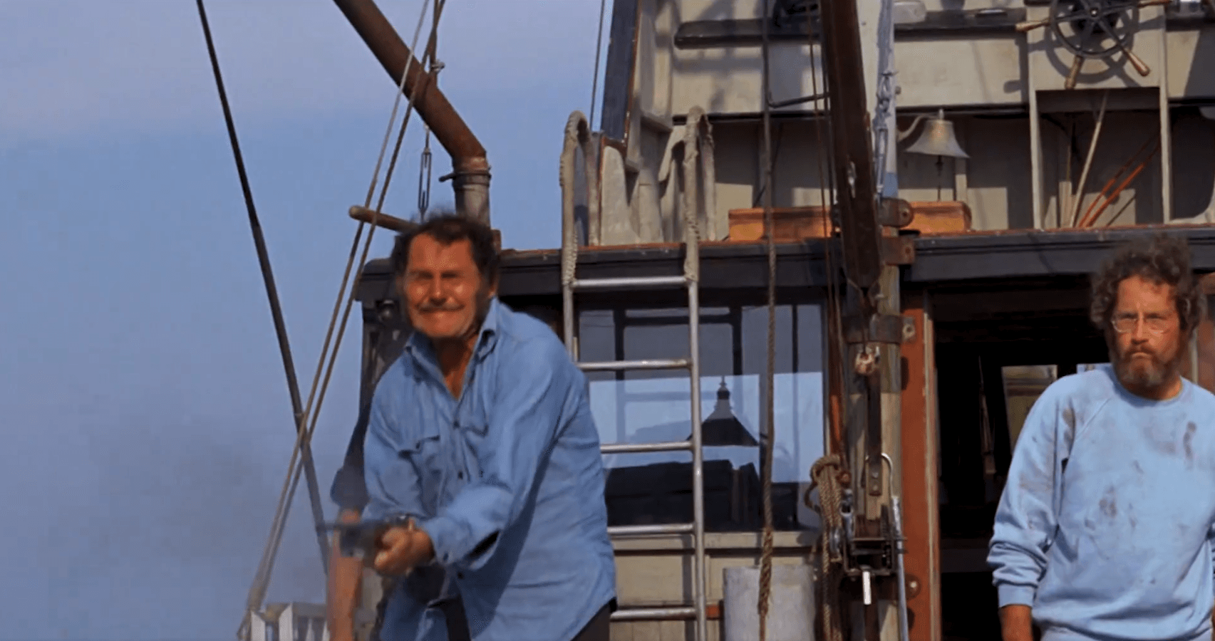 Two sailors on ship deck with maritime equipment and blue sky