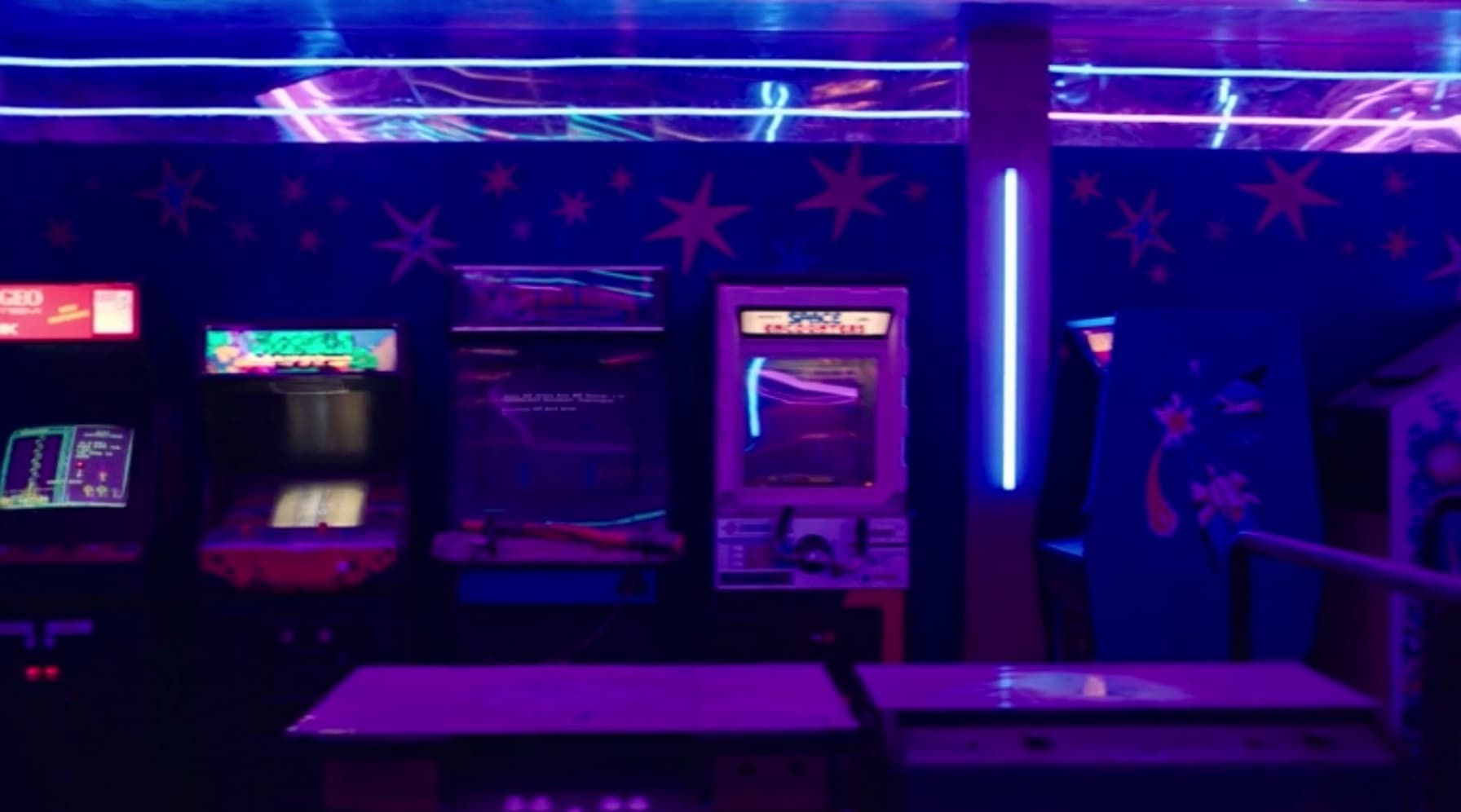 Neon-lit arcade with glowing screens, purple and blue color palette