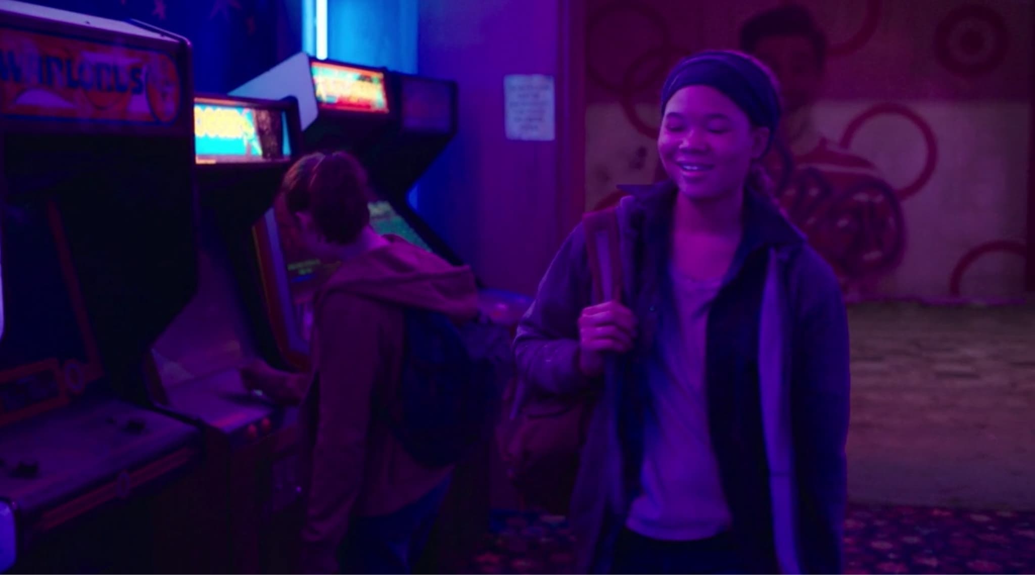 Smiling person in arcade with purple and blue neon lighting