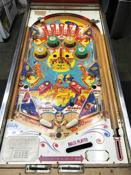 The Moon Shot playfield photographed on a shop floor, its space-themed art showing astronauts, rockets and planets around a central rotating target