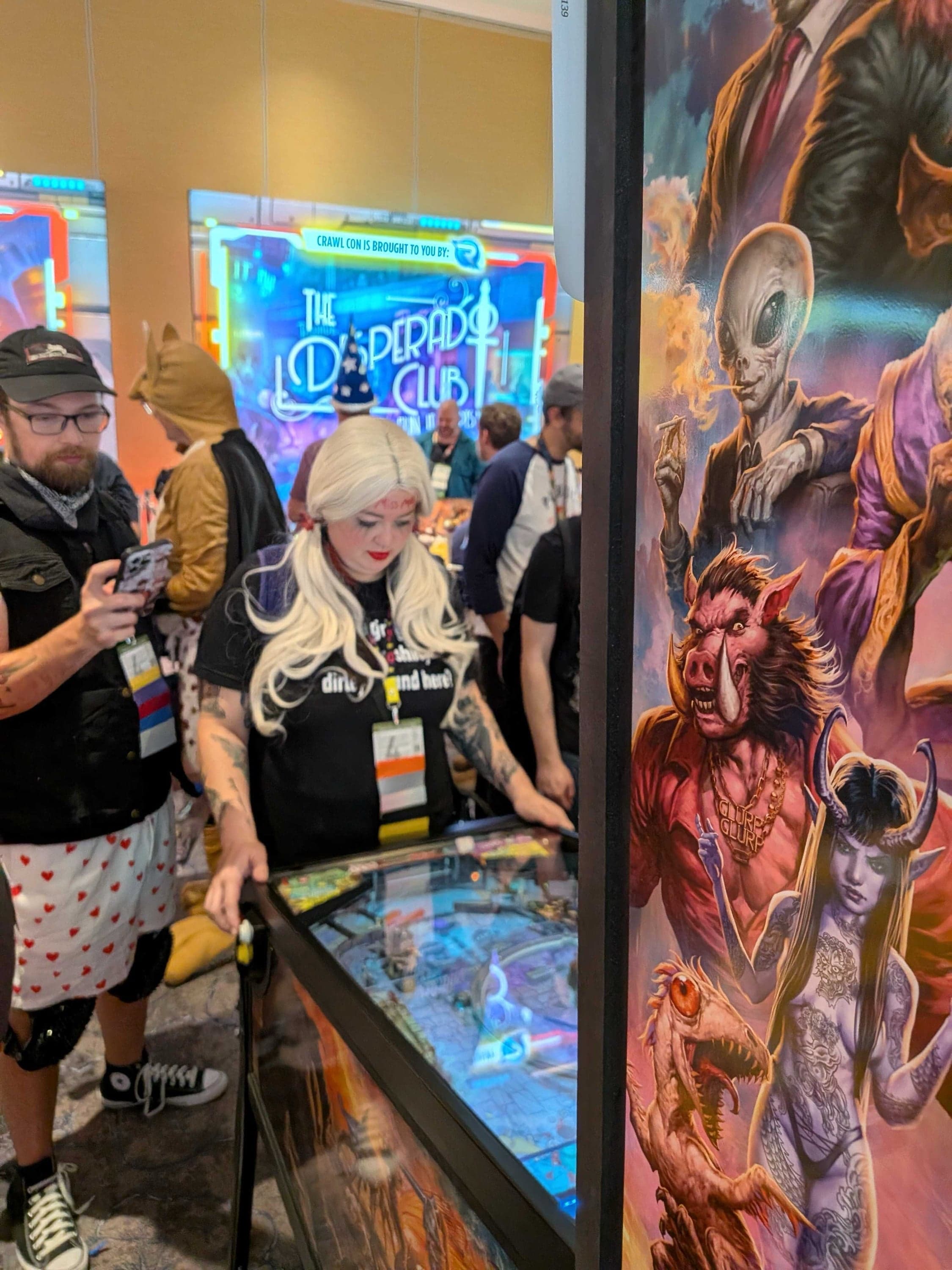 Two attendees playing Dungeon Crawler Carl pinball