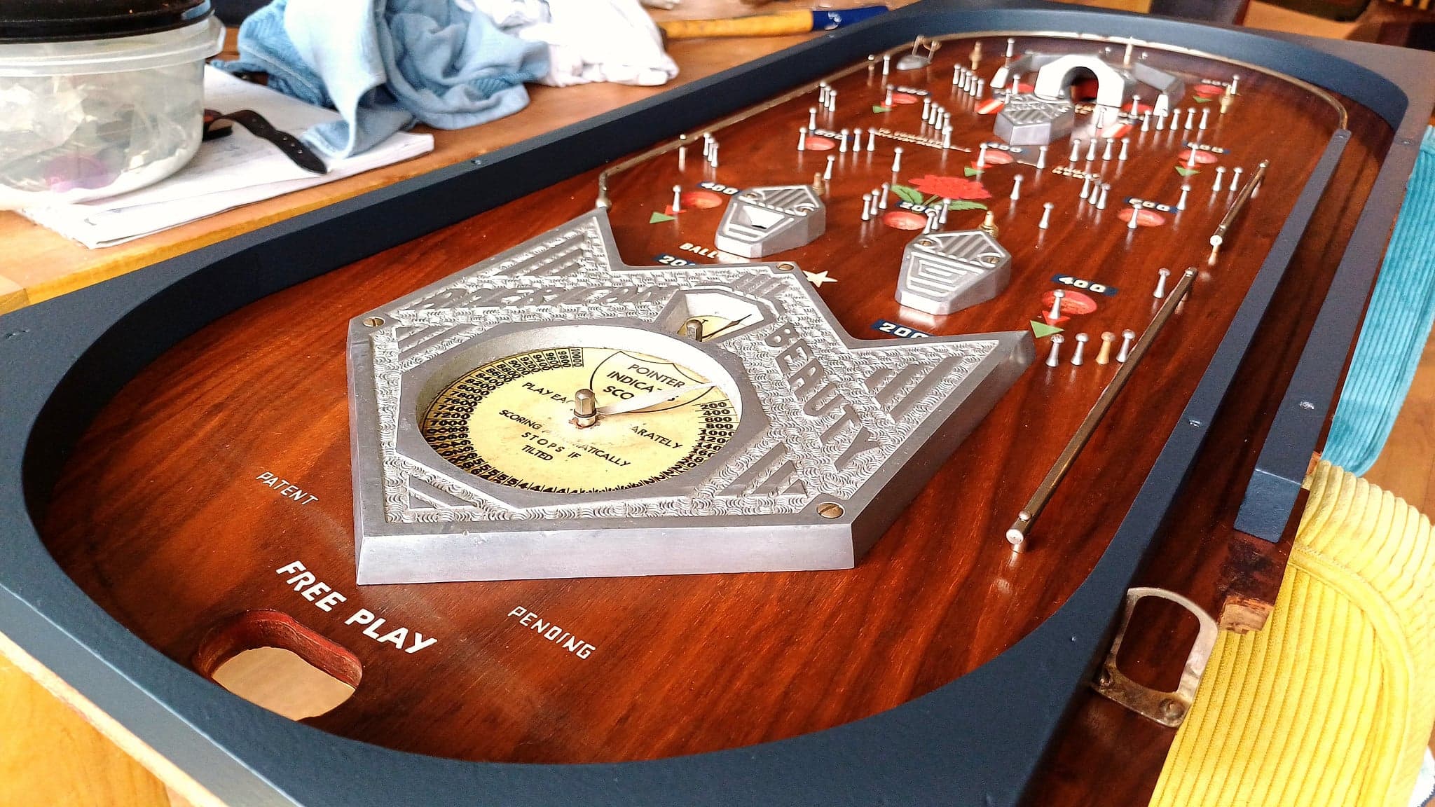 American Beauty playfield on a workbench during restoration, its rosette score dial at the centre, Daval Manufacturing Company, 1934