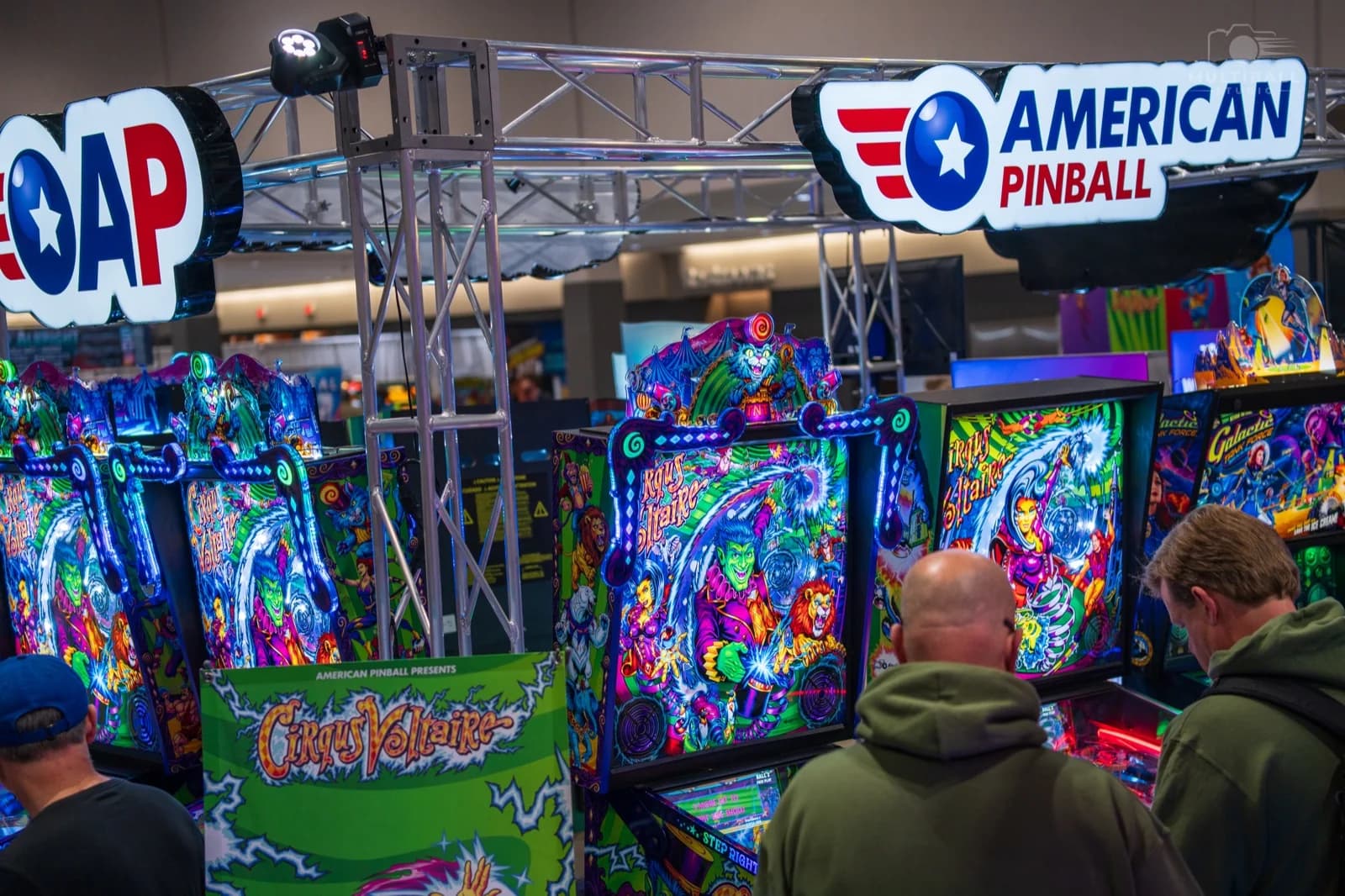 Players at American Pinball's Expo 2026 booth with Cirqus Voltaire machines and a Galactic Tank Force