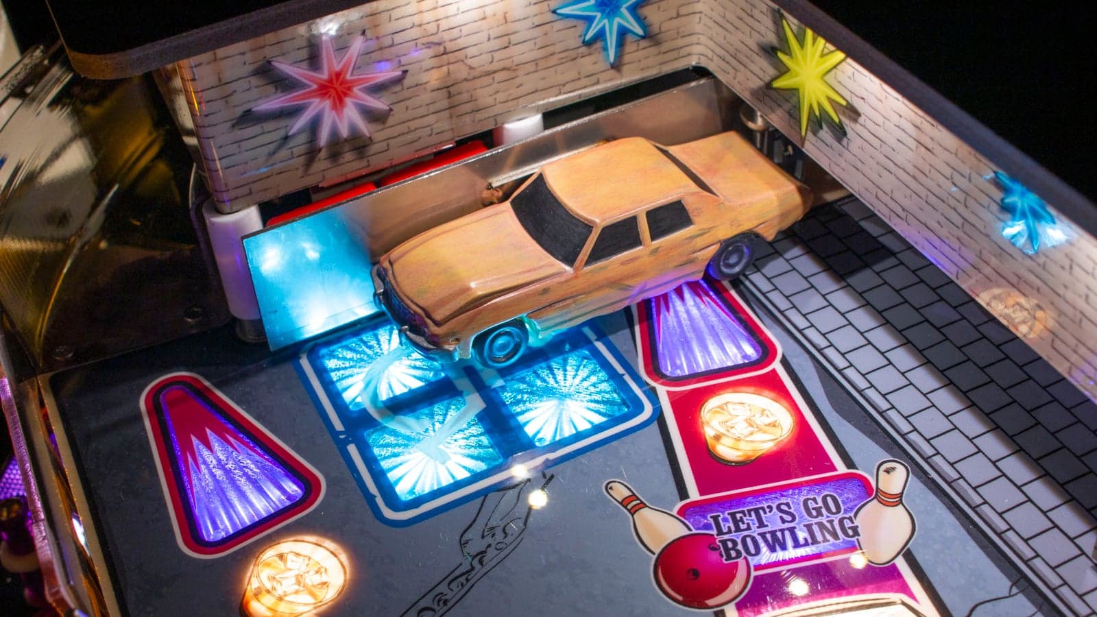 The Dude's Car bash toy on the playfield above a lit Let's Go Bowling insert