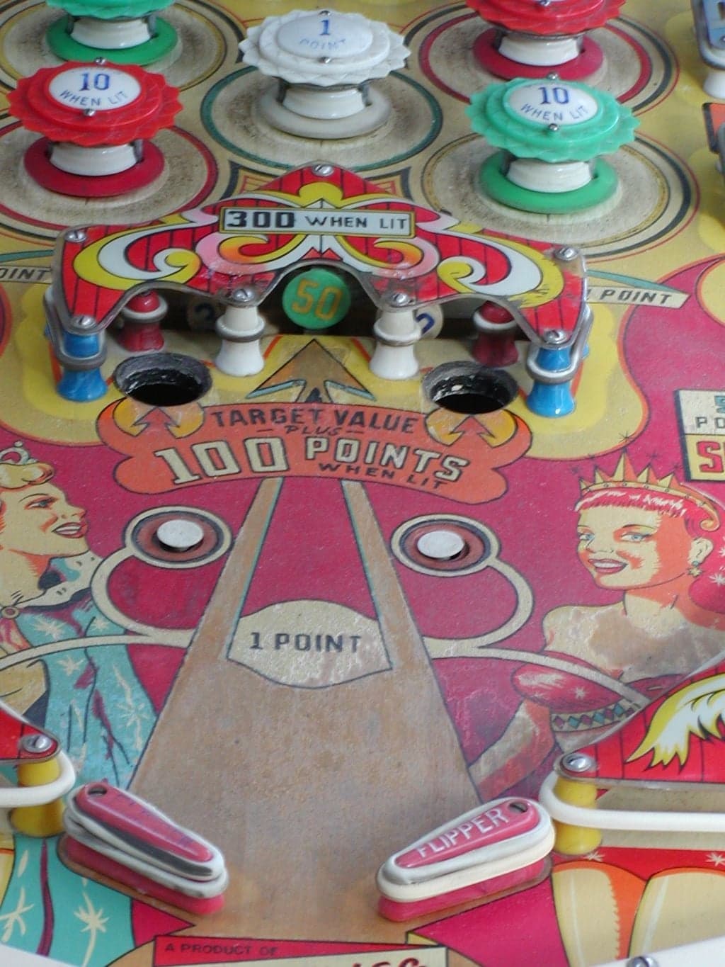 The roto-target on a Majestic playfield: a rotating disc showing a green 50 panel, set into a decorated arch marked 300 when lit, with pop bumpers above and the flippers below