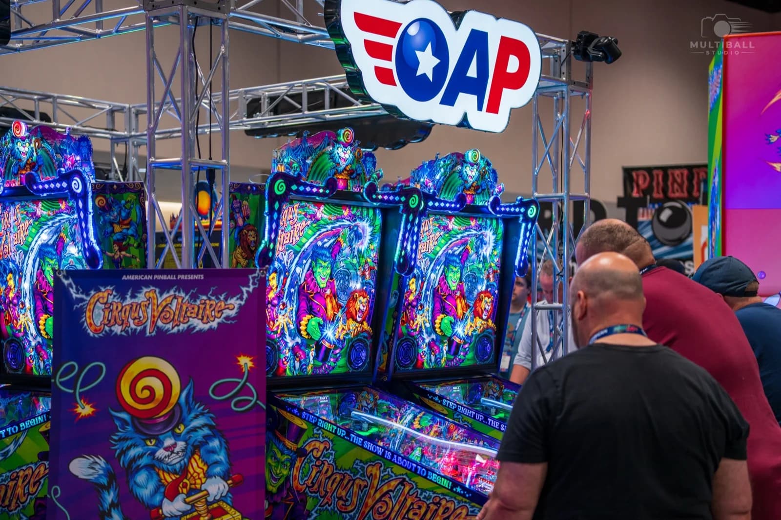 Cirqus Voltaire machines lined up under the AP sign at Pinball Expo 2026, with players in the foreground