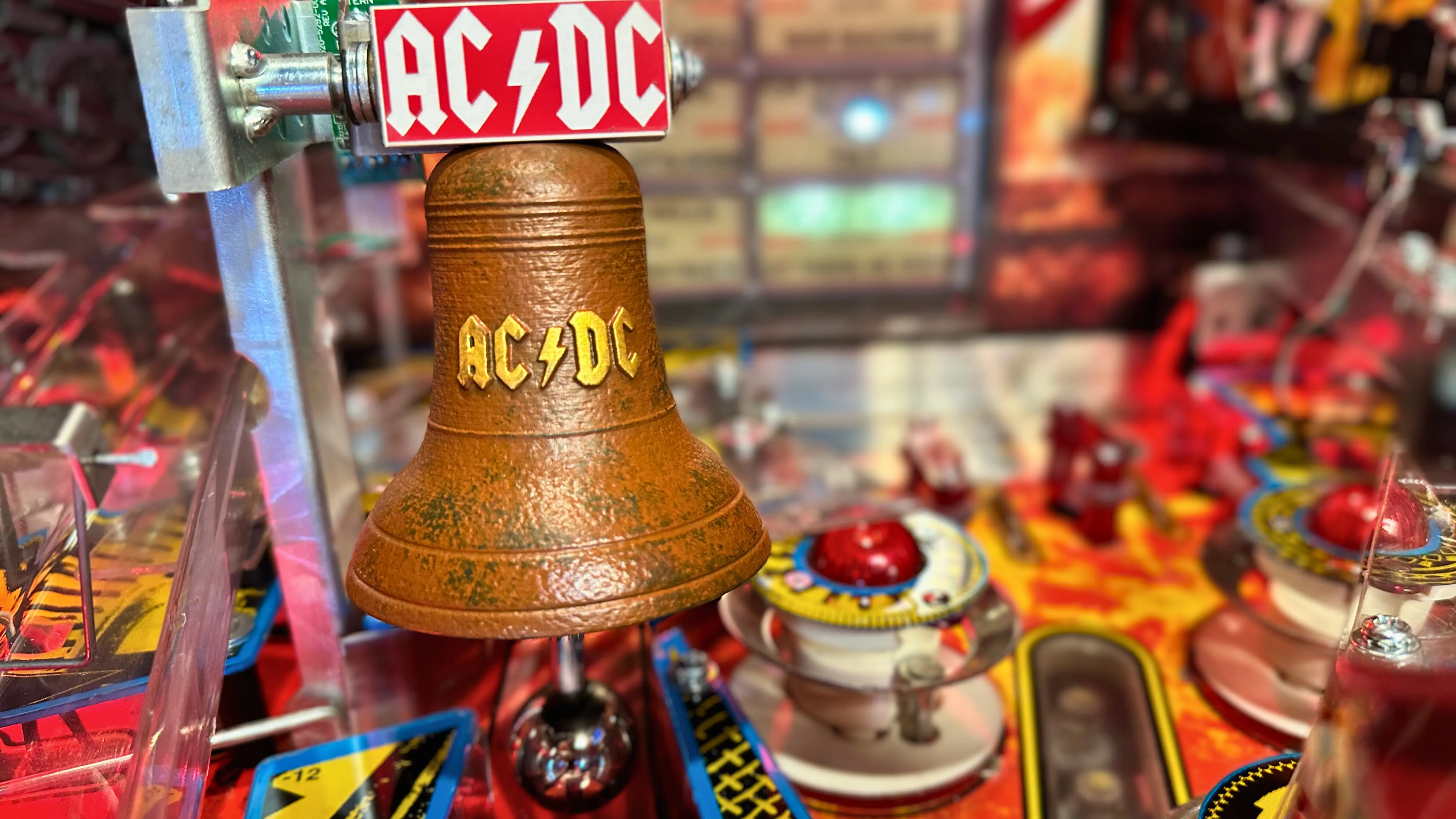 AC/DC branded bell on a colorful vintage pinball machine