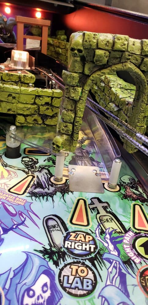 Spooky skull-themed pinball machine with green stone archway and colorful playfield