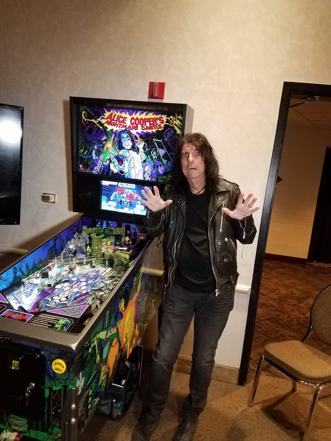 Rock musician poses with Alice Cooper themed pinball machine