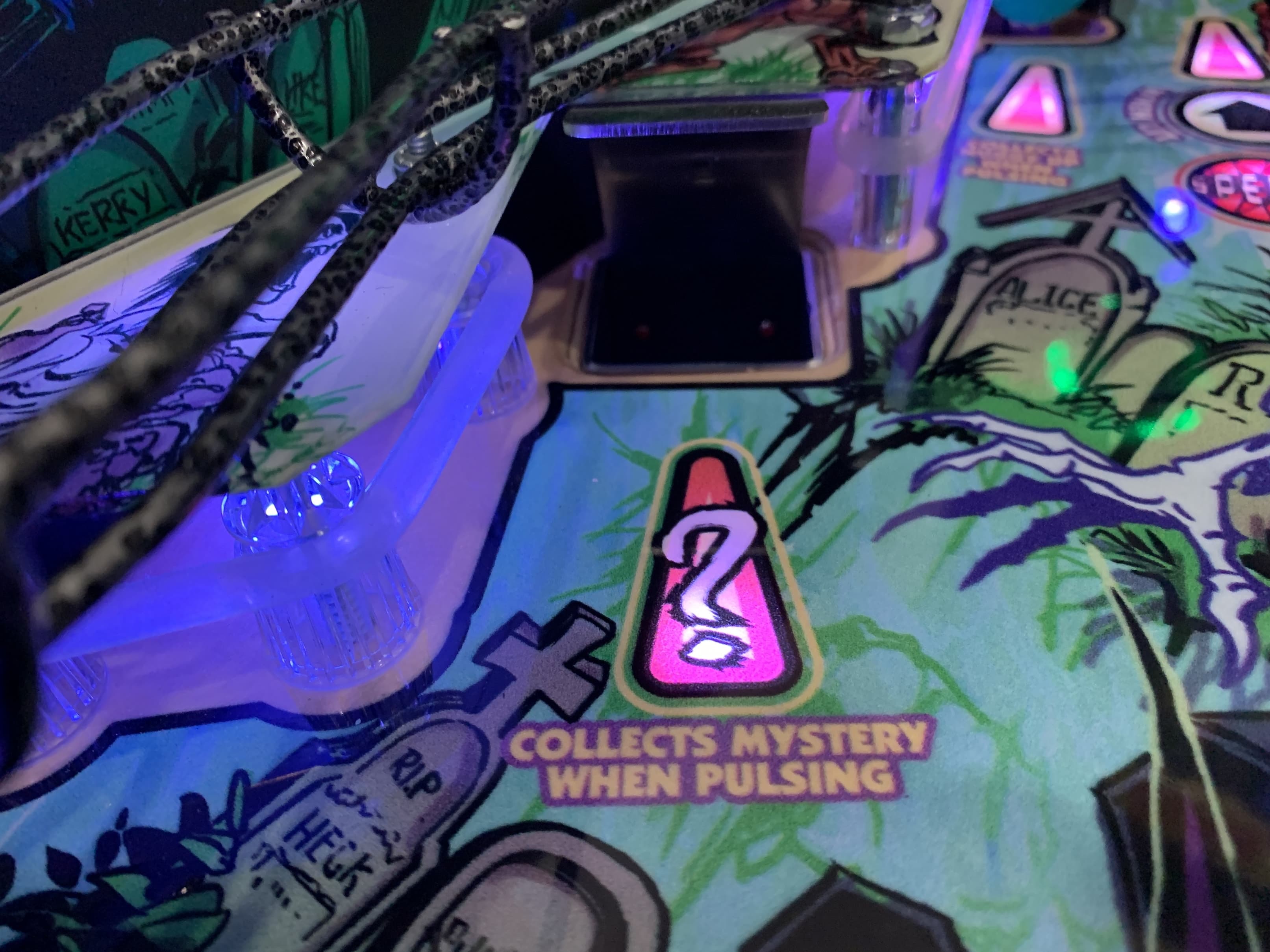 Pinball machine detail with glowing pink and blue mysterious game element