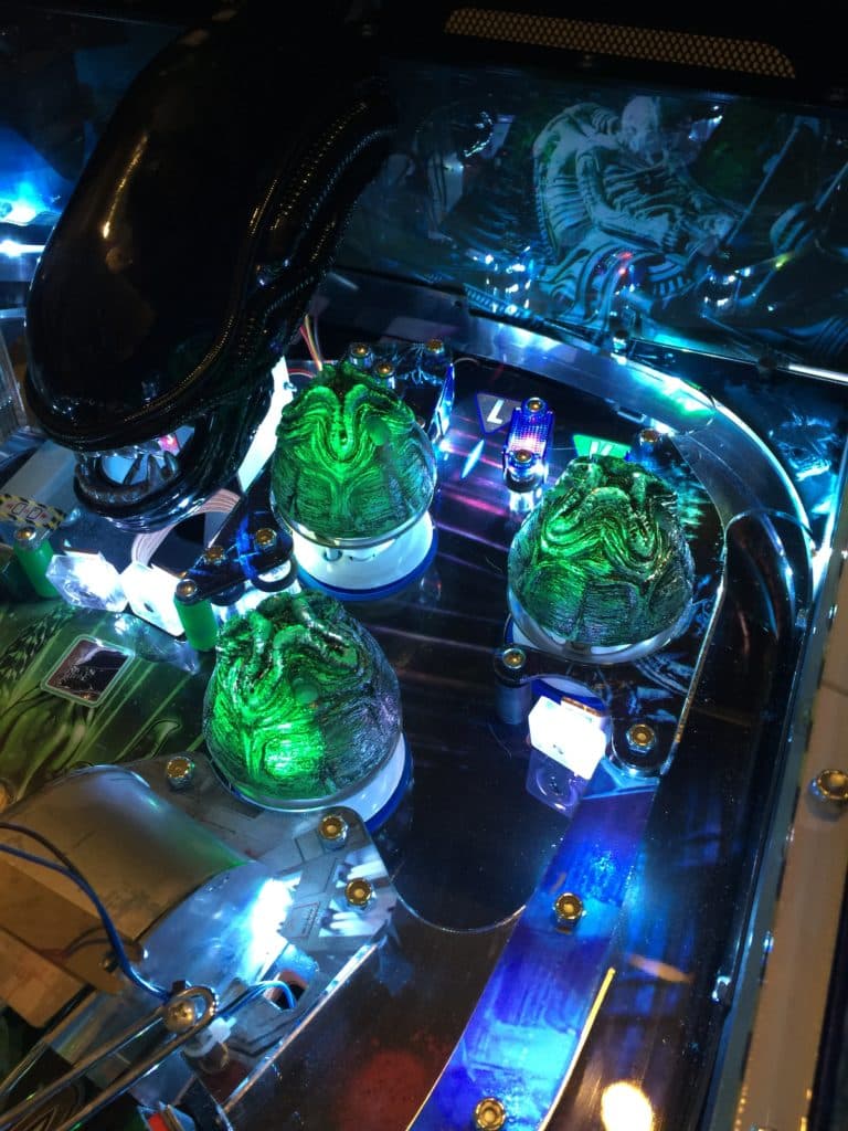 Alien eggs glowing green on illuminated sci-fi themed pinball machine