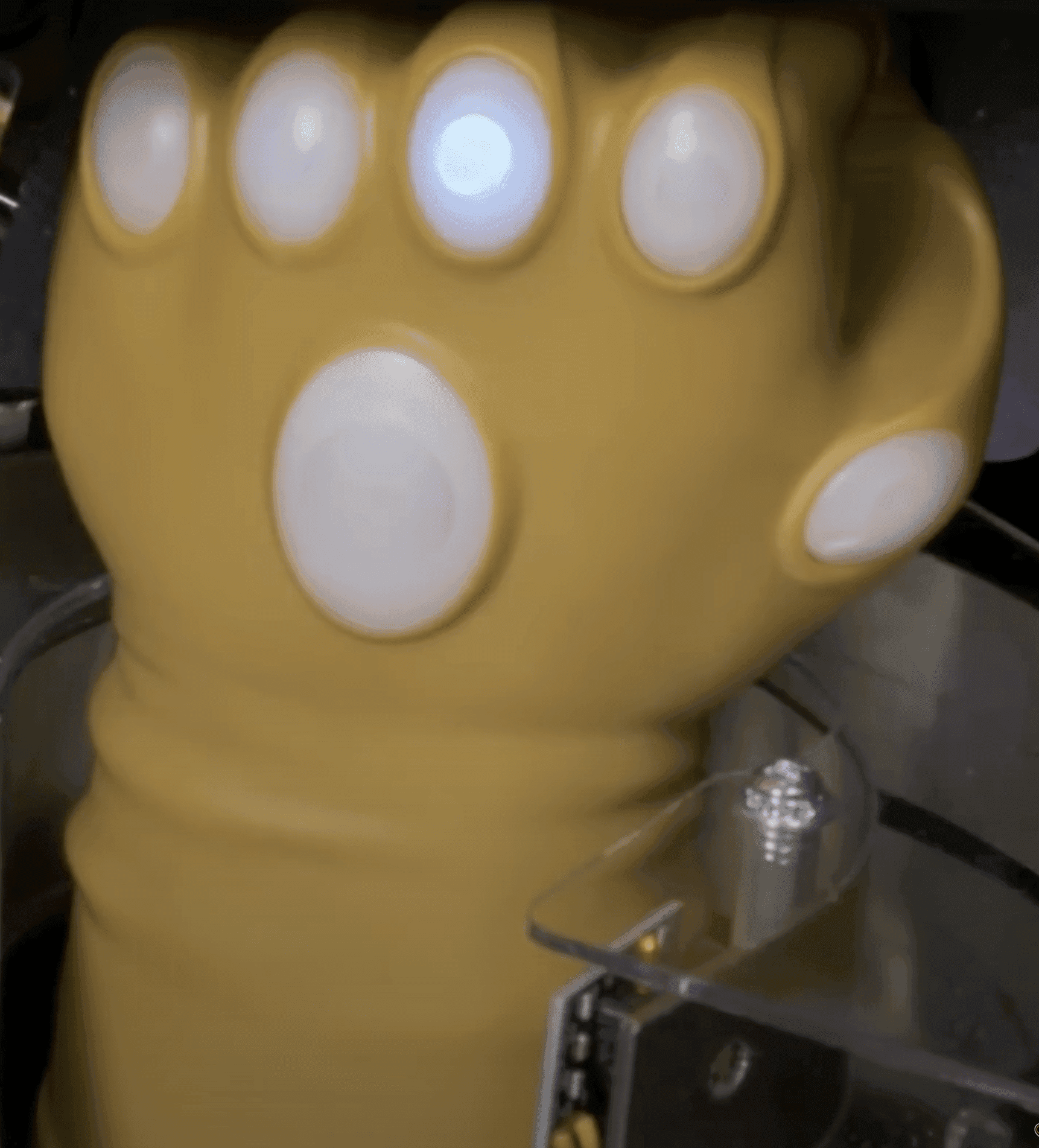 Yellow robotic glove with white circular sensors, close-up view