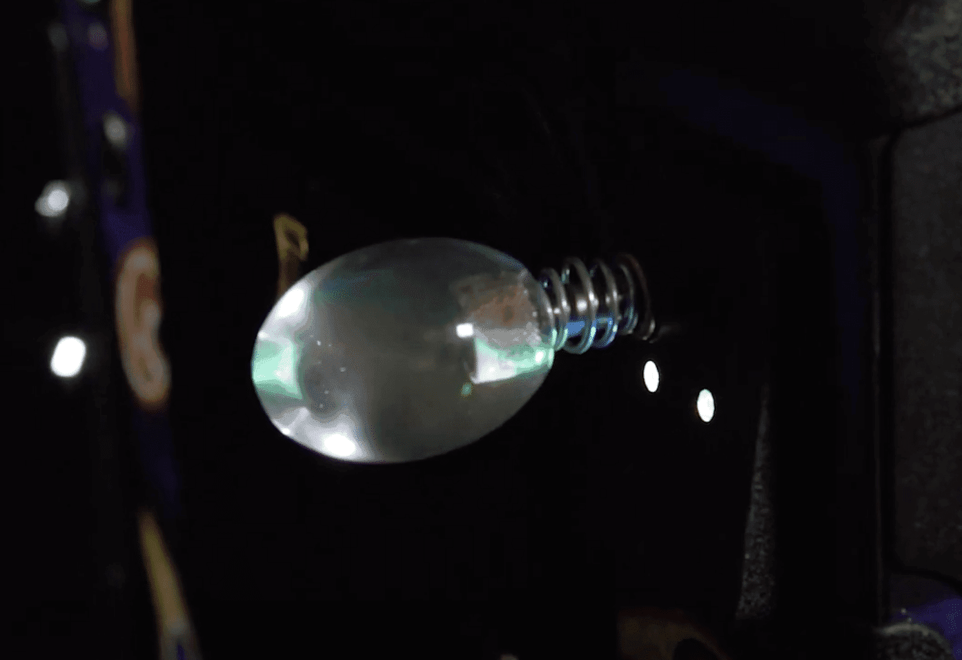 Translucent light bulb with metallic base against dark background