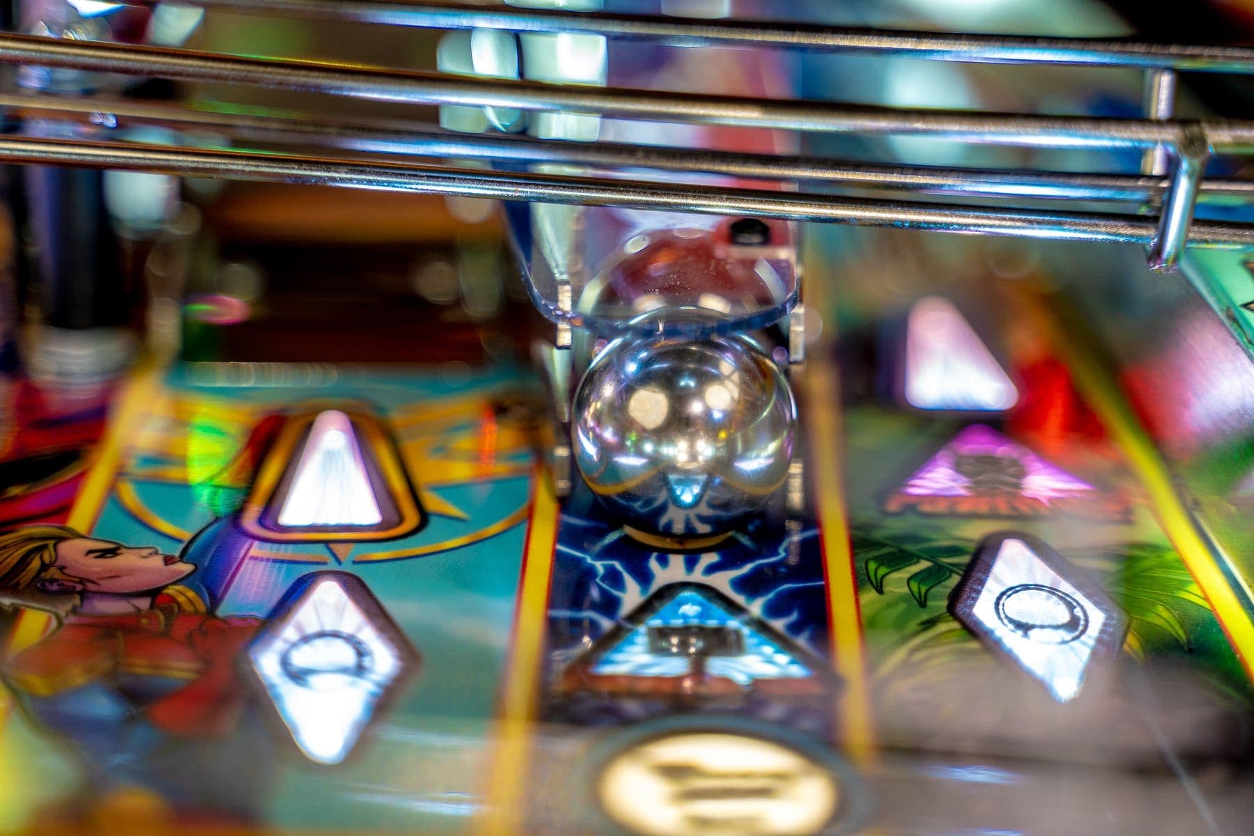 Closeup of colorful pinball machine with shiny silver ball and illuminated buttons