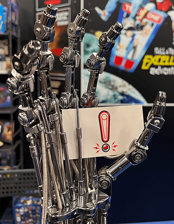 Metallic robotic hand holding an exclamation mark note
