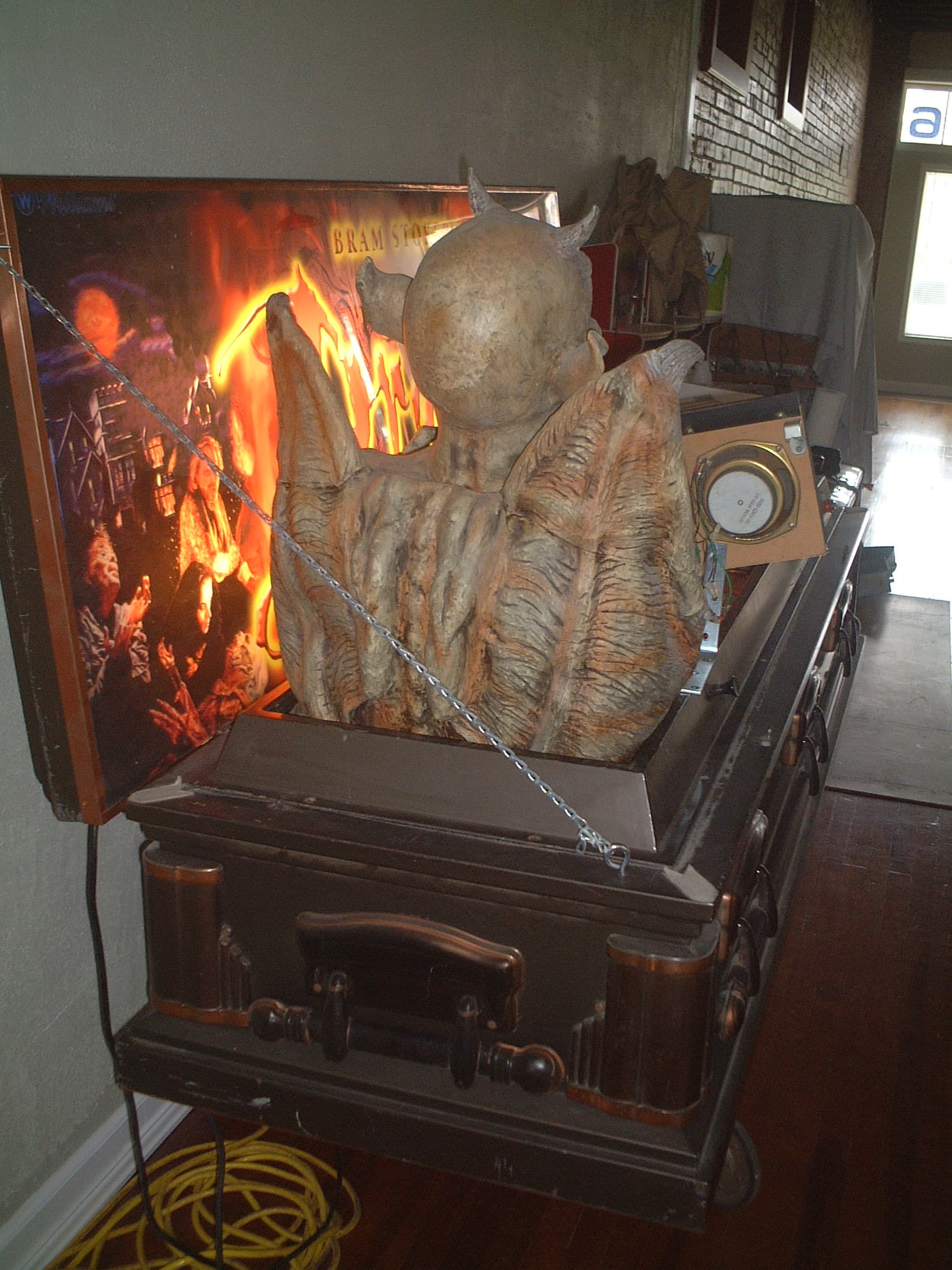 Chained demonic creature statue near vintage stove with fiery background