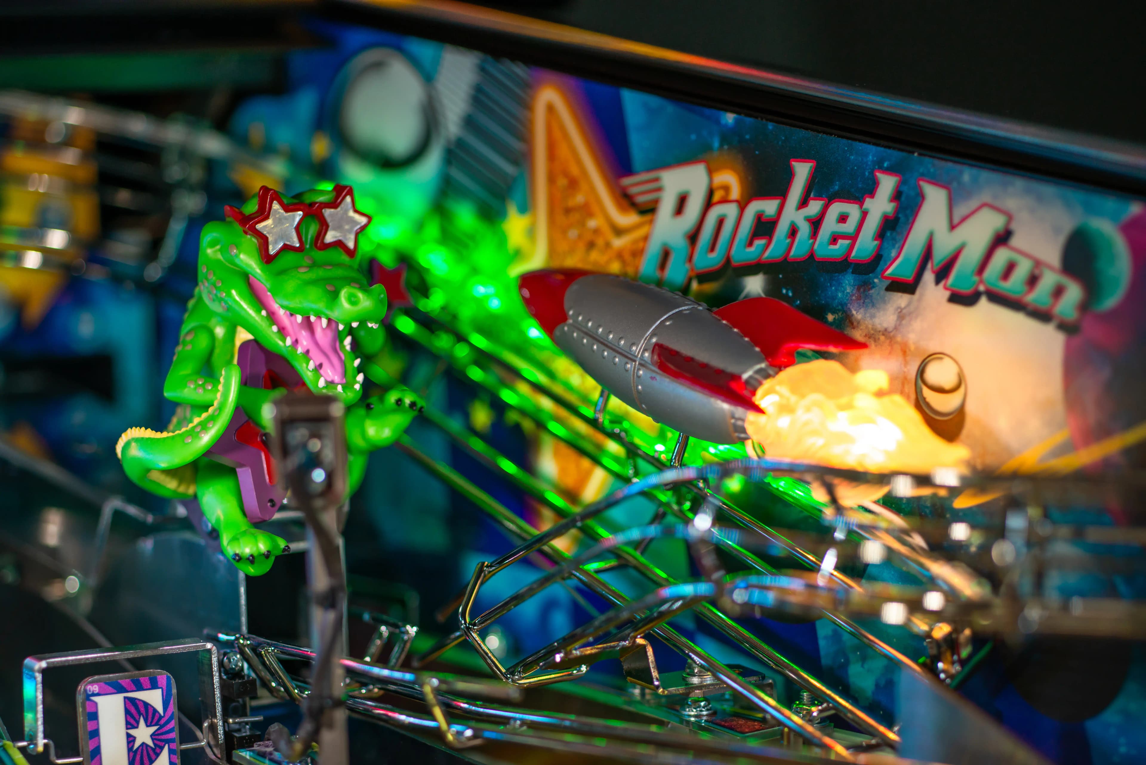 Green cartoon dinosaur with star glasses on Rocket Man pinball machine
