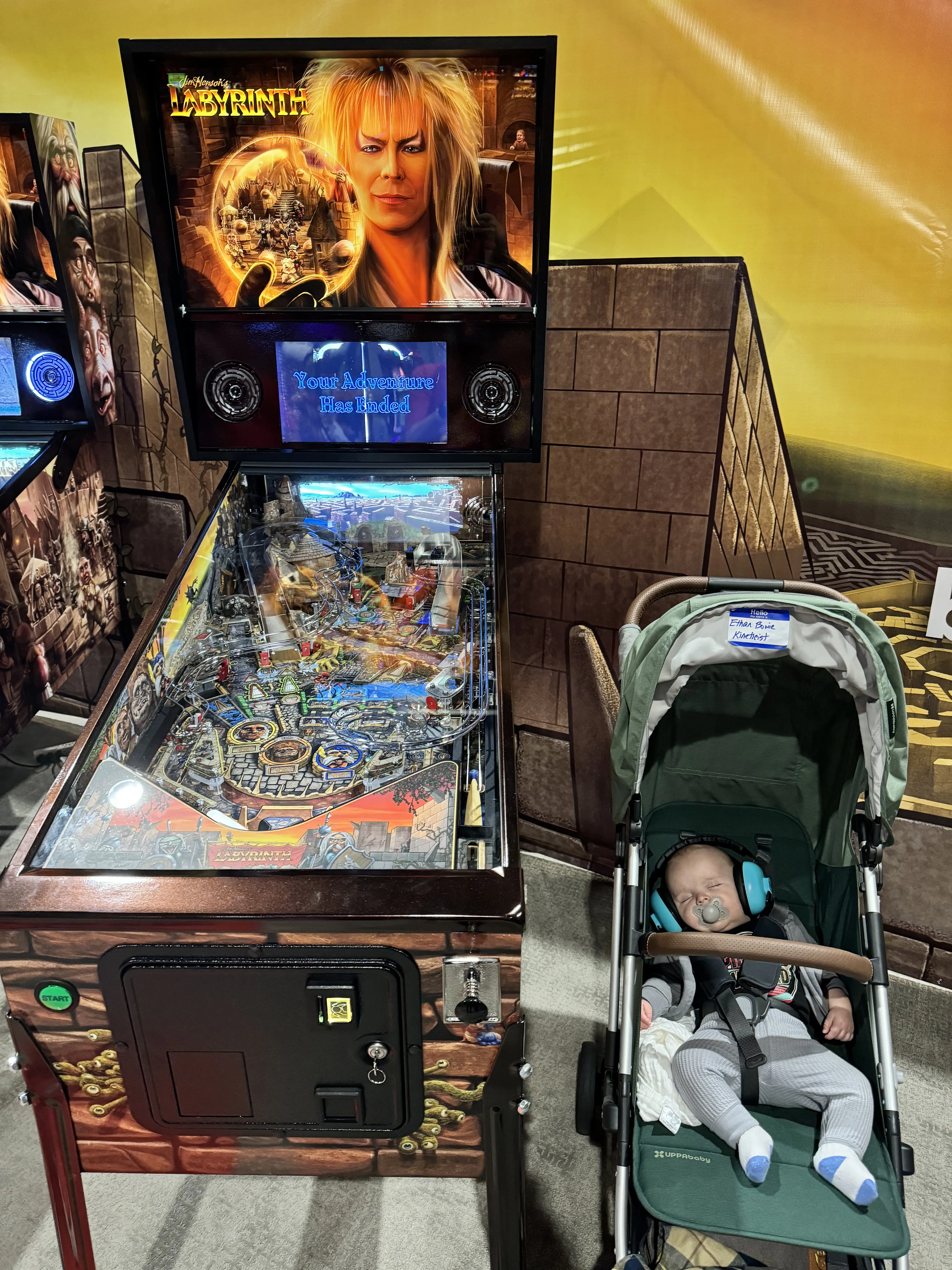 Labyrinth pinball machine with sleeping baby in stroller nearby