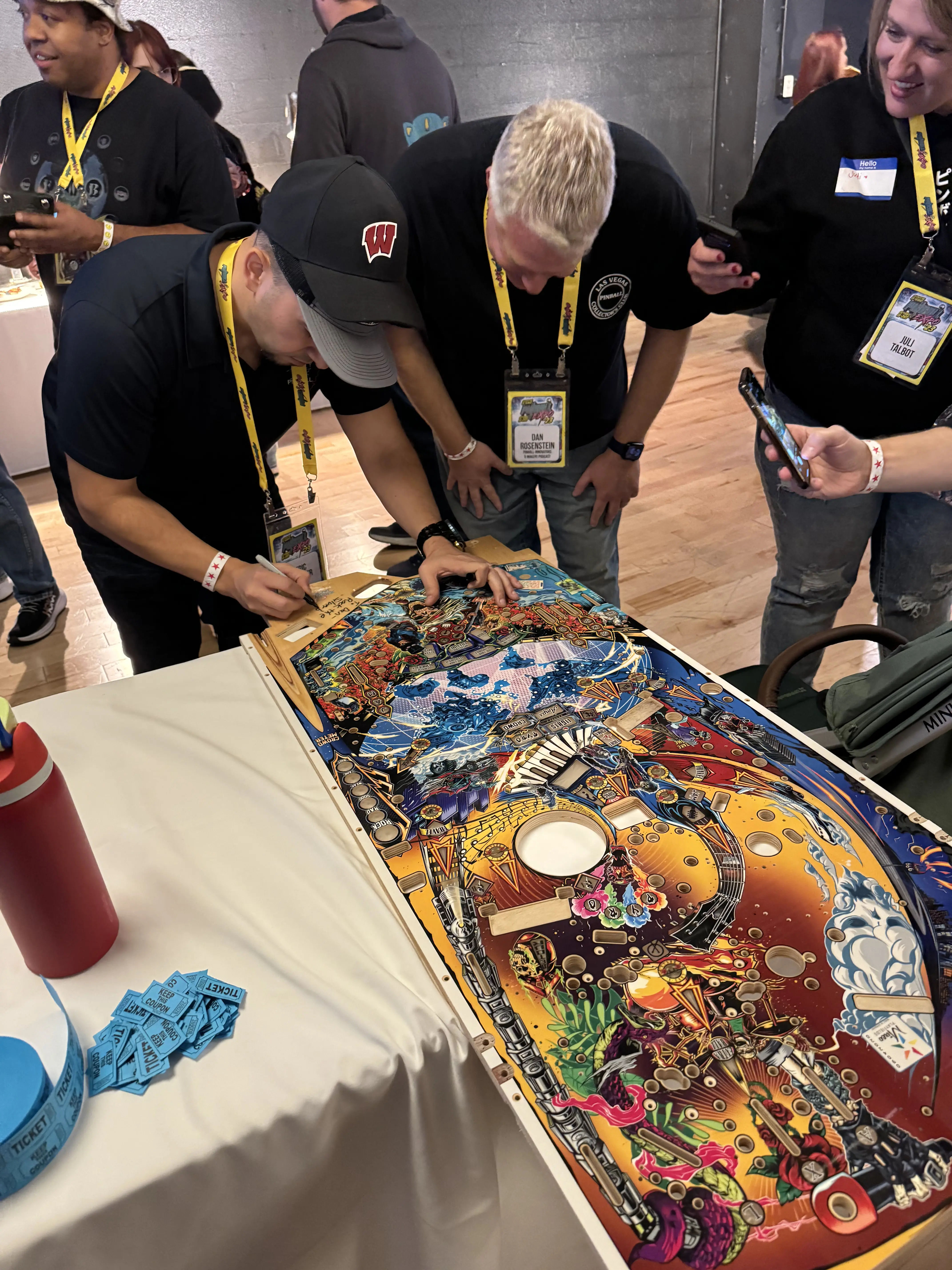 People examining colorful pinball machine at gaming convention event