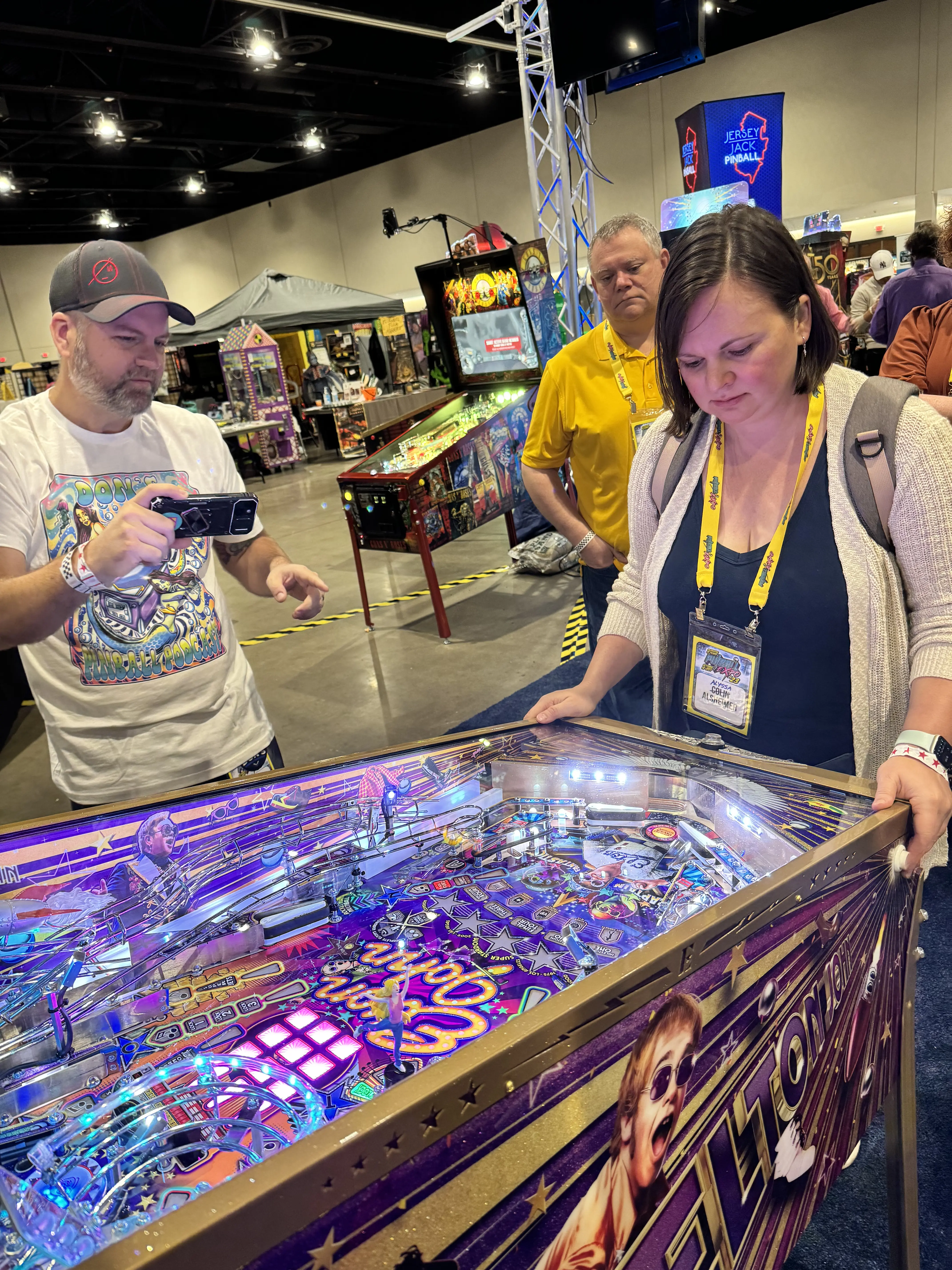 Colorful pinball machine with players at gaming convention