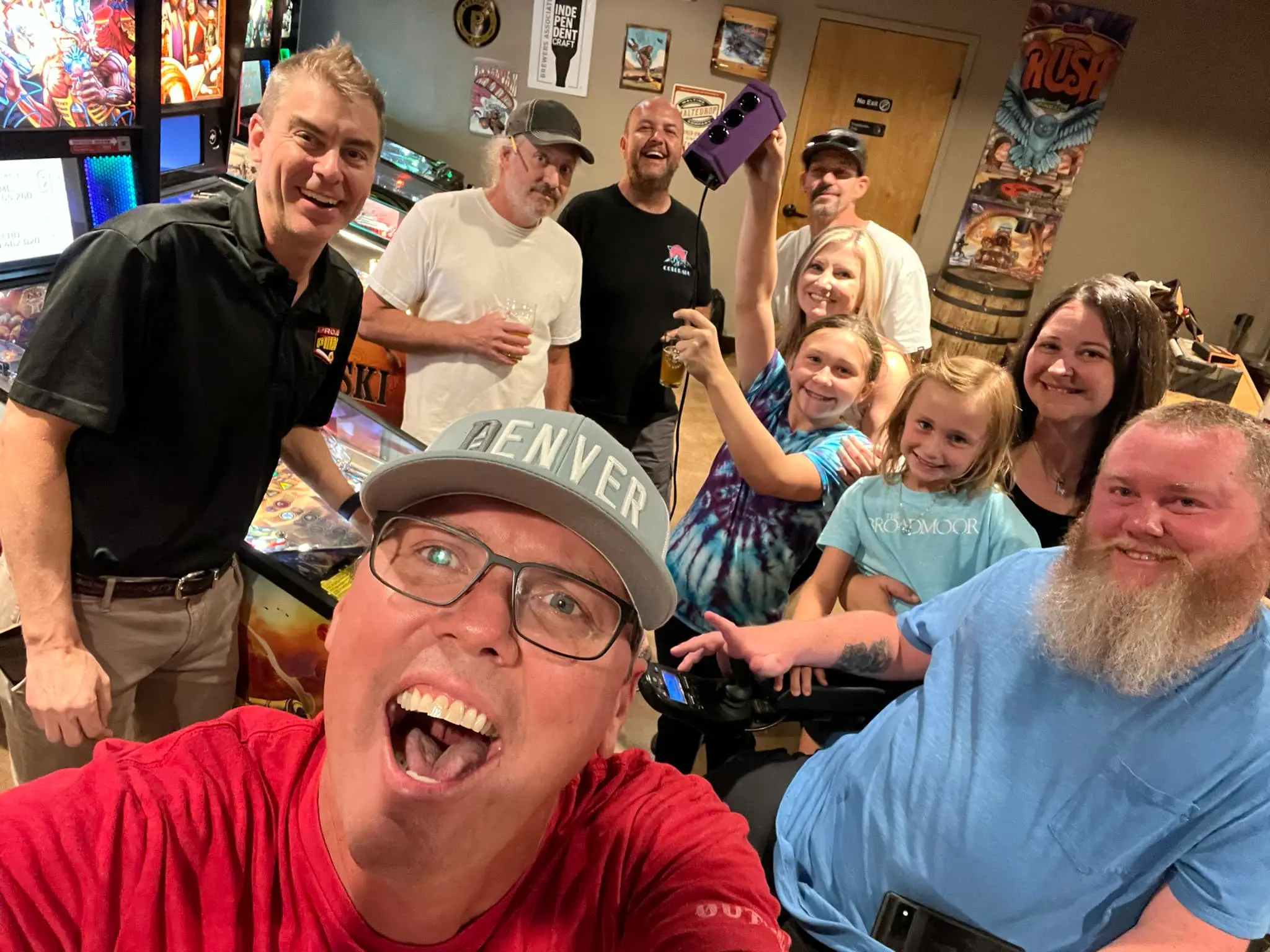 Large group of people smiling together in a colorful room with posters