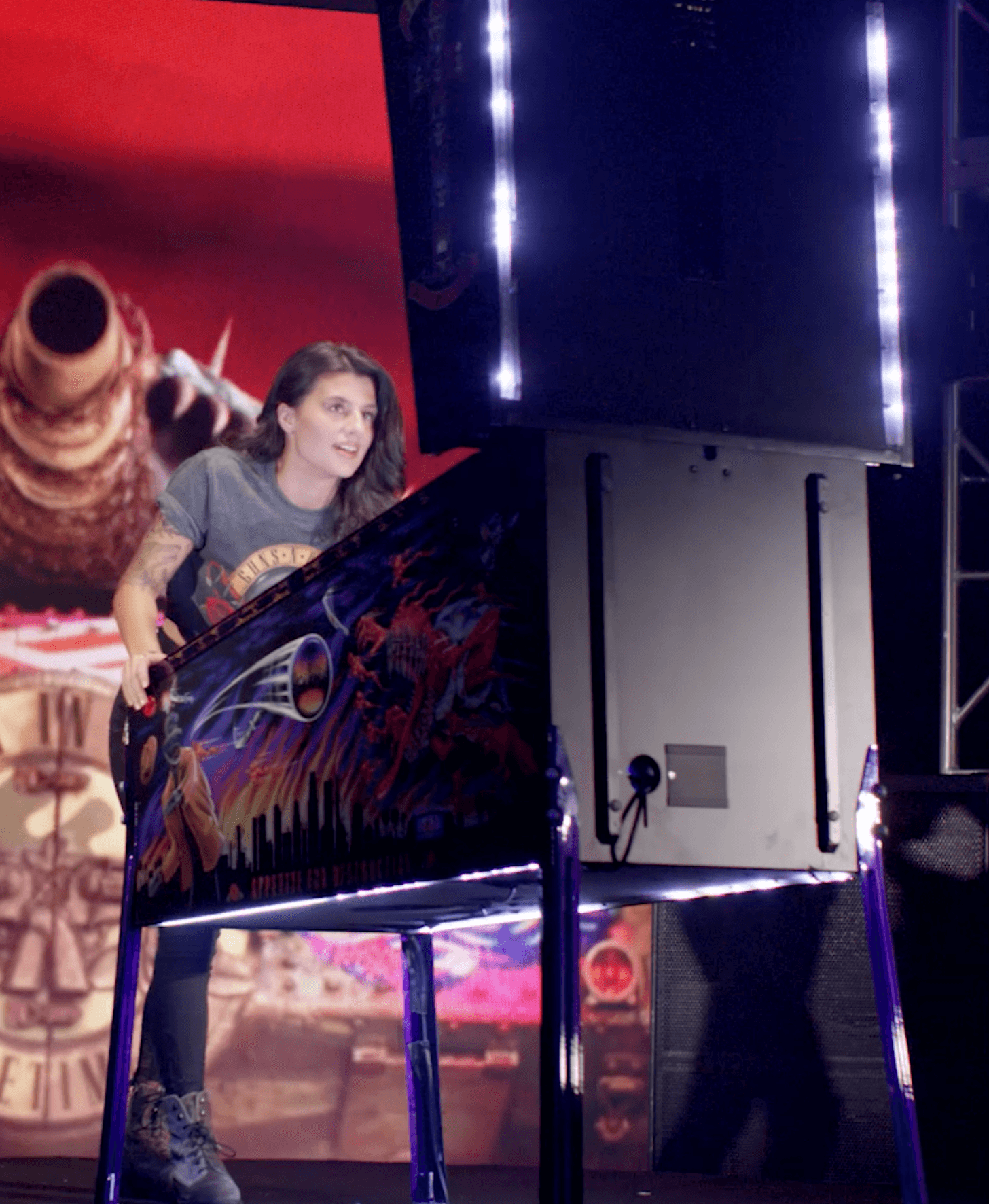 Person standing on stage with large display screen and dramatic lighting