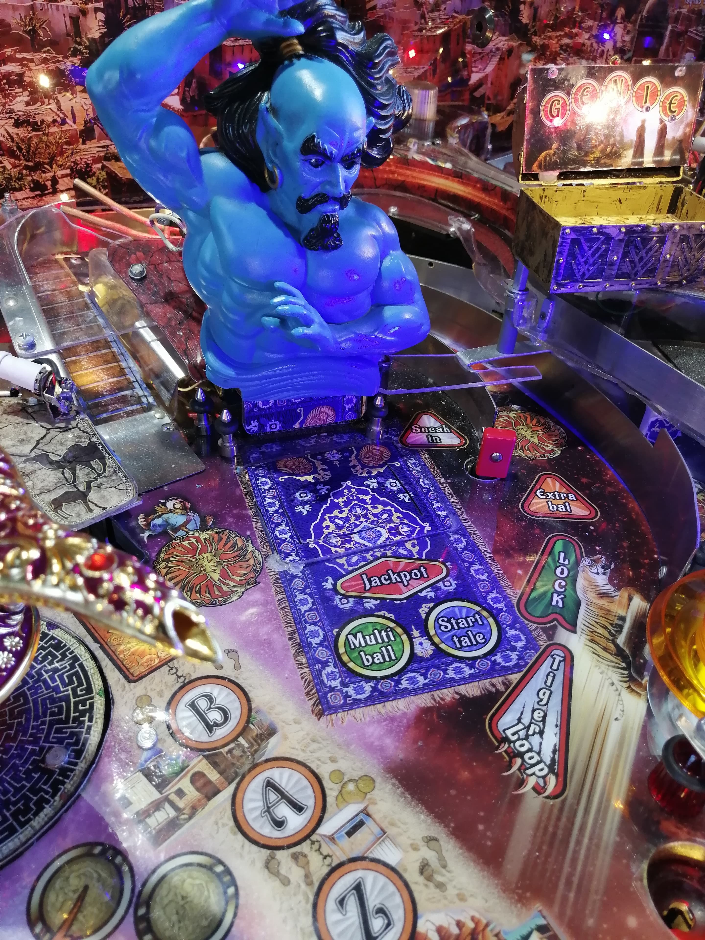 Blue mystical genie figure on colorful pinball machine with game elements