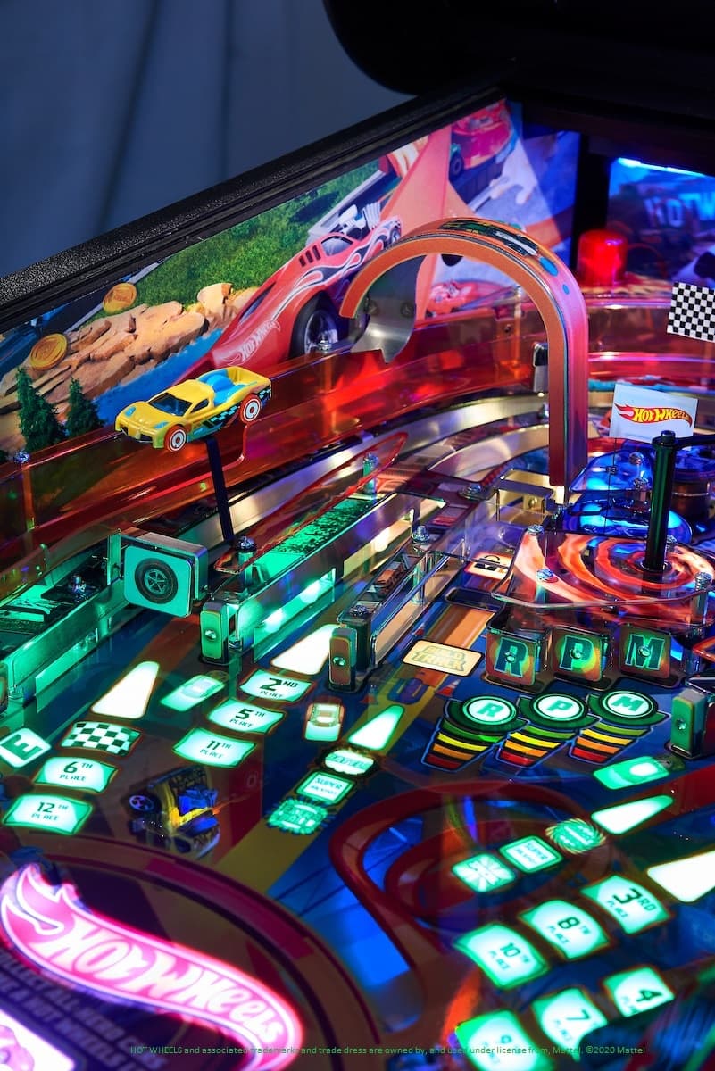 Colorful Hot Wheels pinball machine with toy cars and glowing green buttons