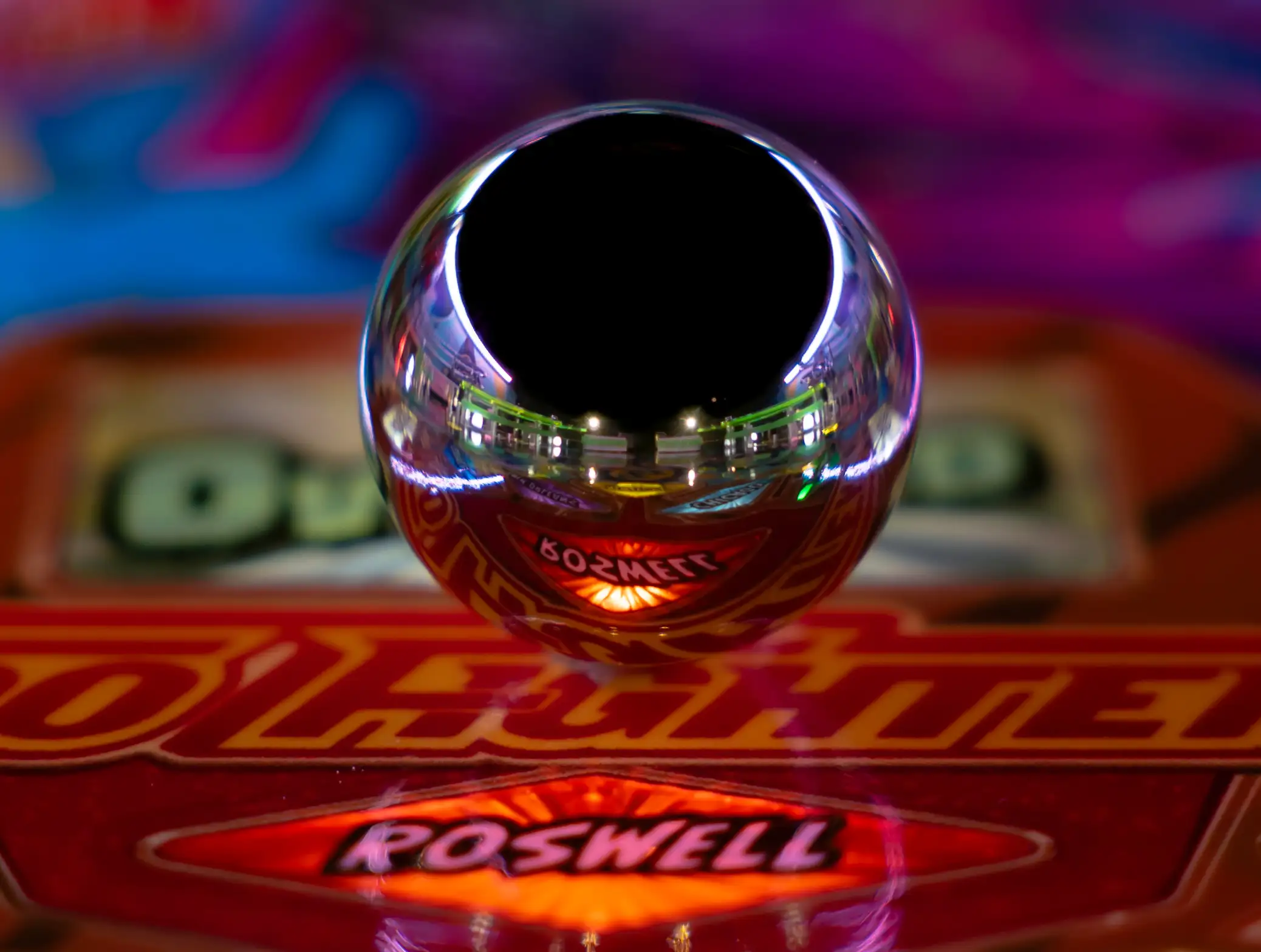 Reflective Roswell-branded chrome ball with colorful background