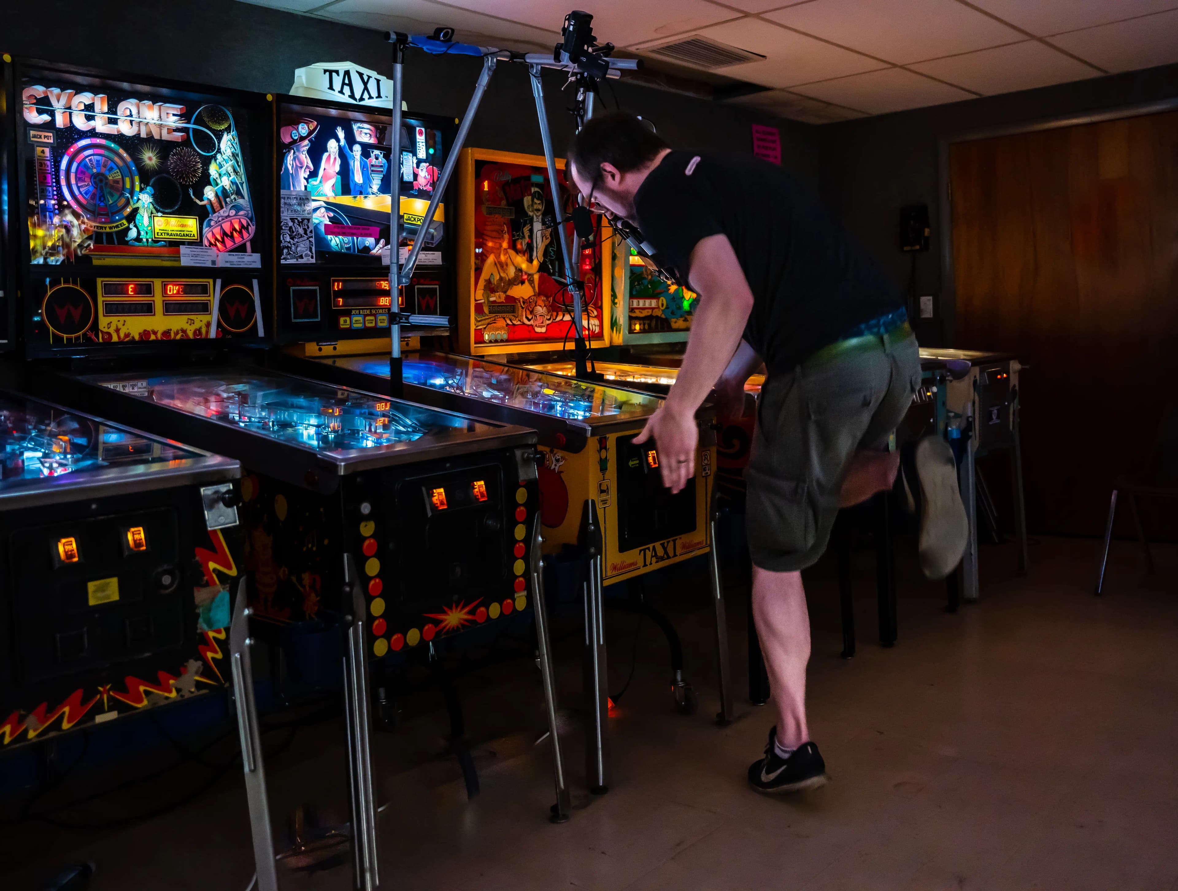 Colorful pinball machines with bright lights in a dimly lit arcade room
