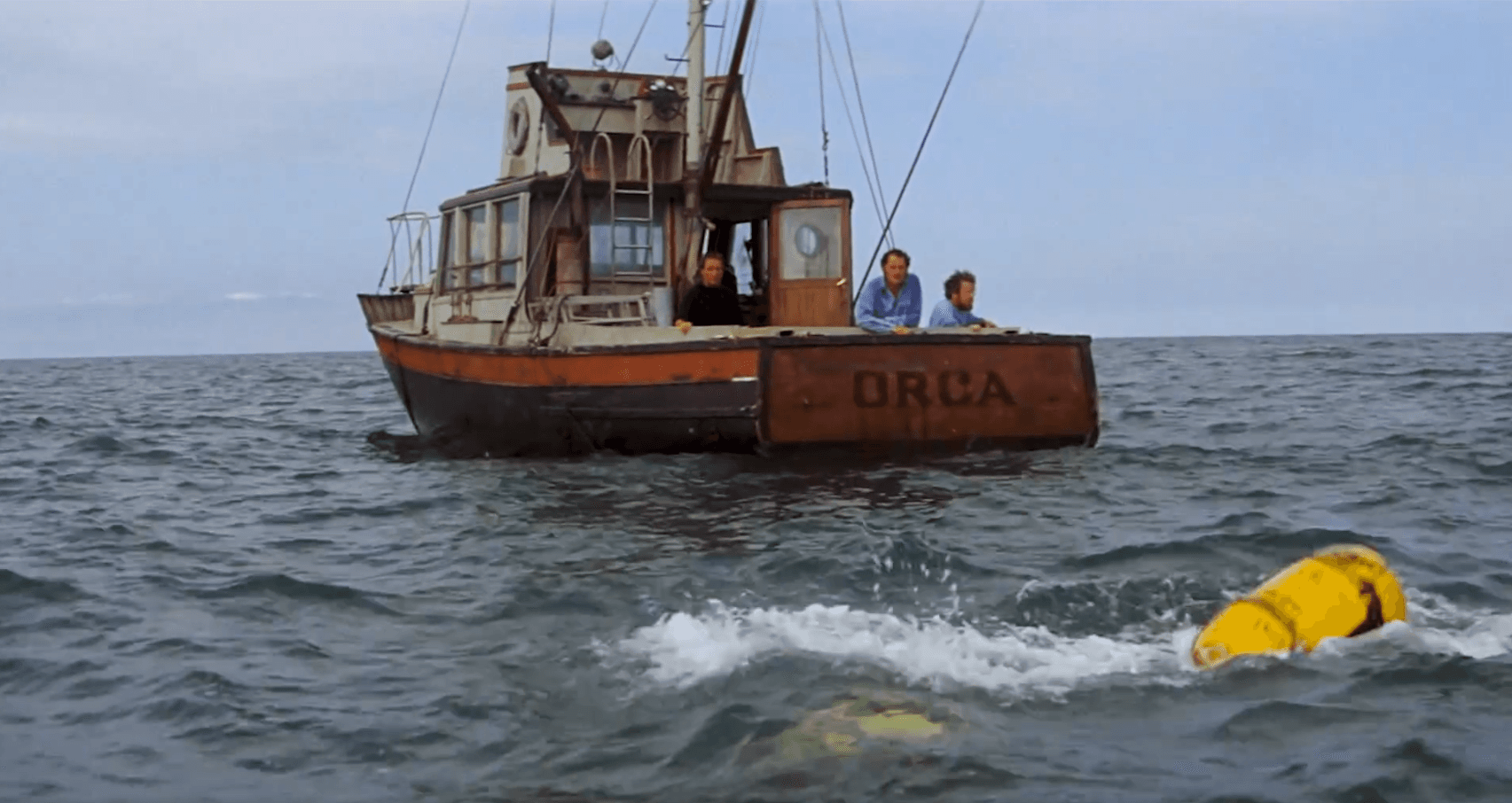 Fishing boat Orca at sea with crew, yellow buoy floating nearby