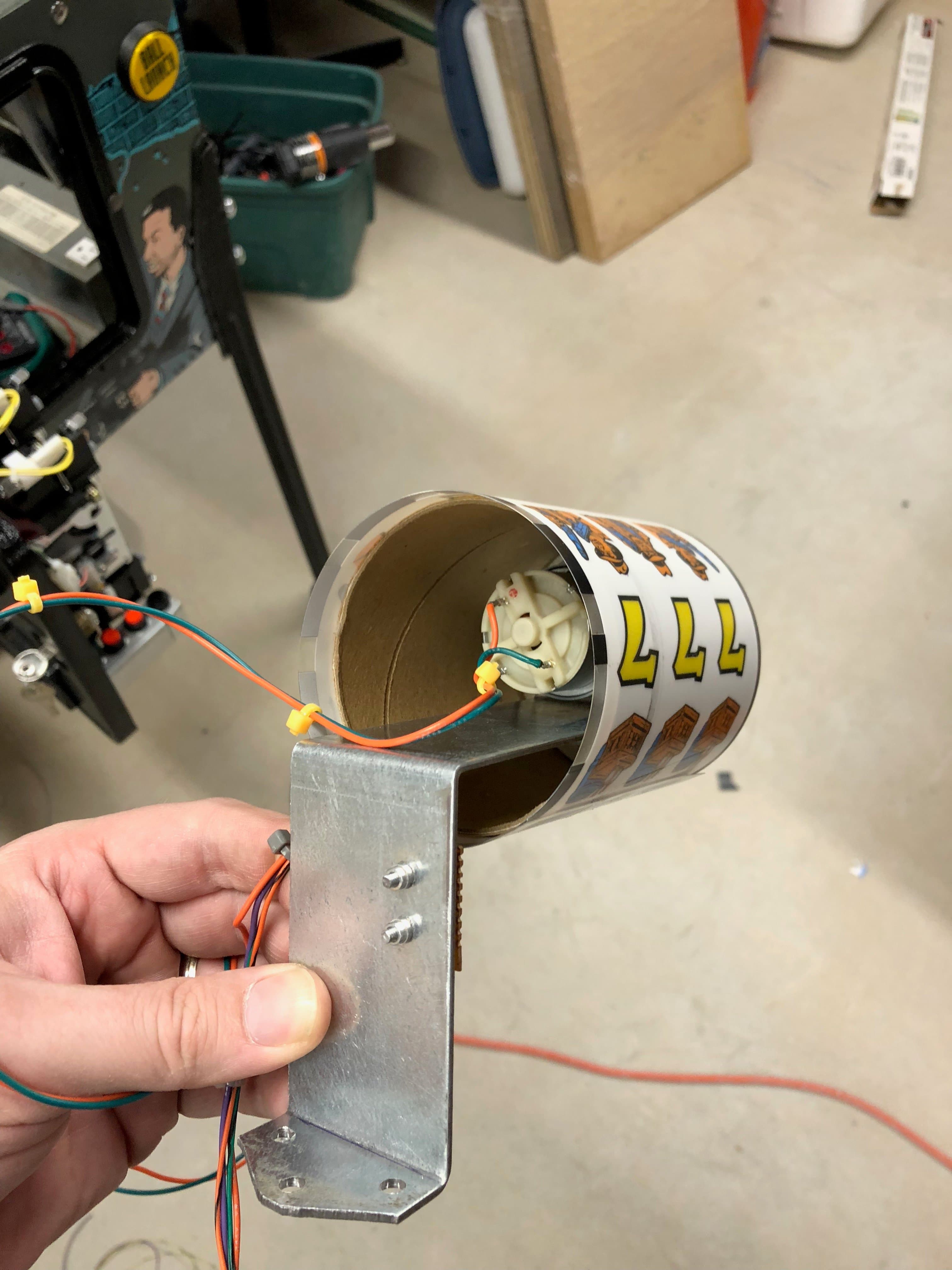 Mechanical device with metal bracket, wires, and coffee cup-like cylinder