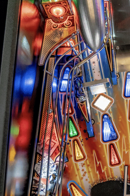 Colorful pinball machine side panel with intricate designs and glowing lights