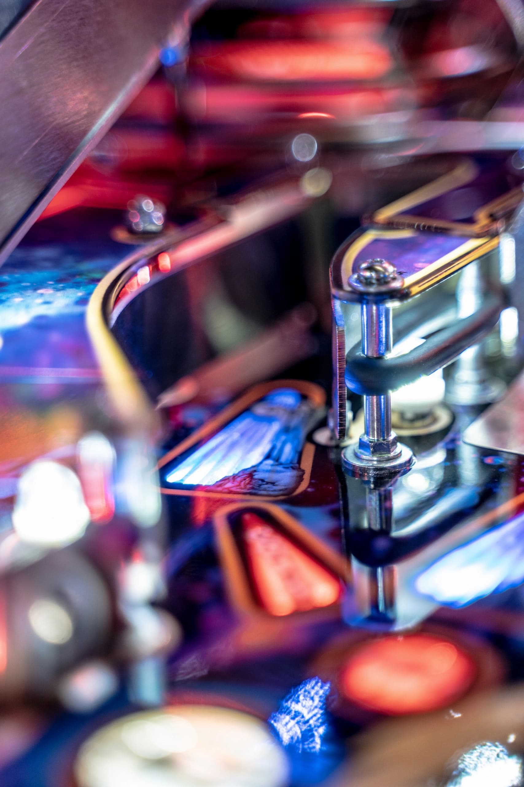 Close-up of colorful pinball machine components with blurred metallic parts