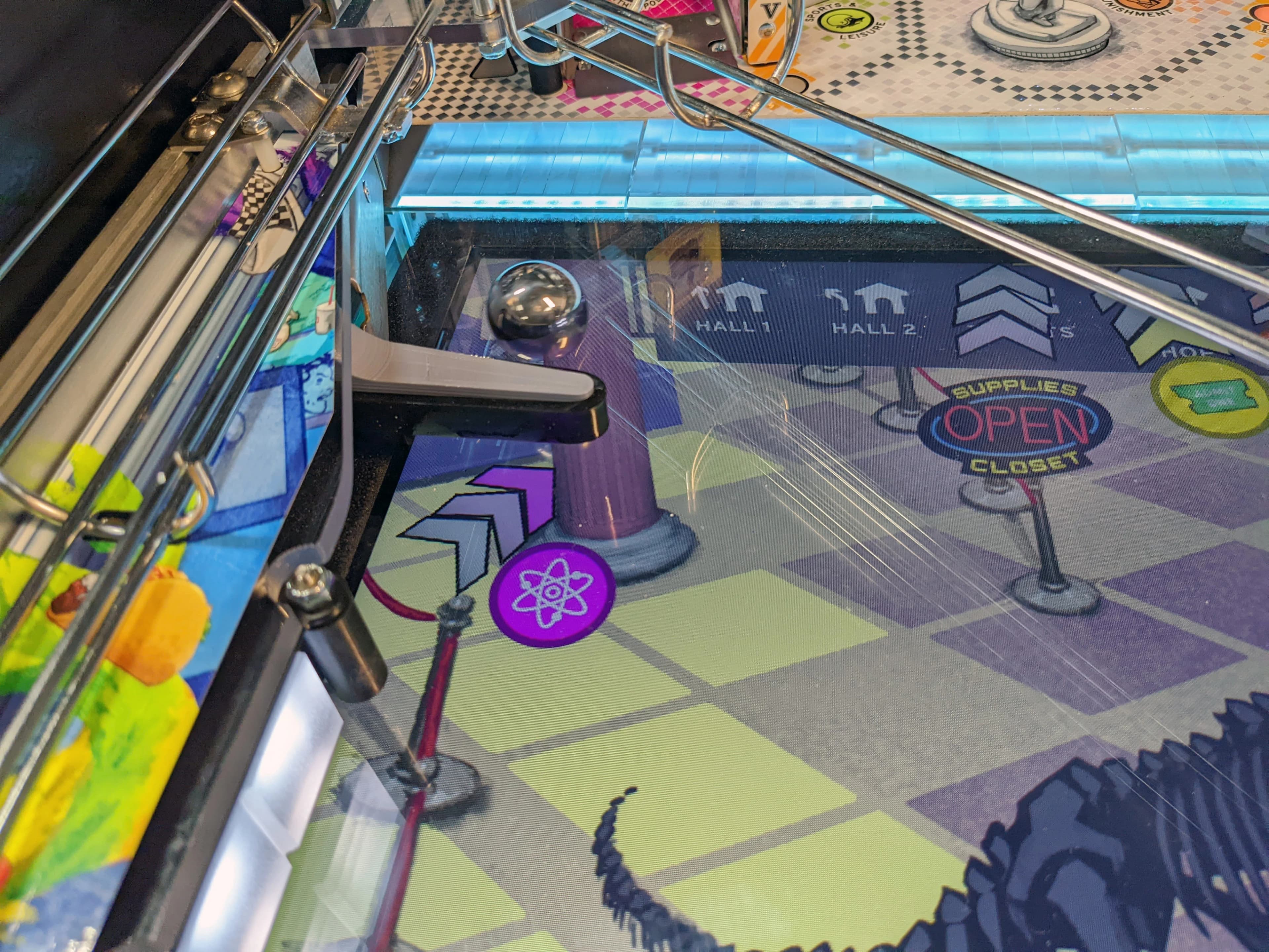 Pinball machine playfield with atom icon, halls, and supplies closet