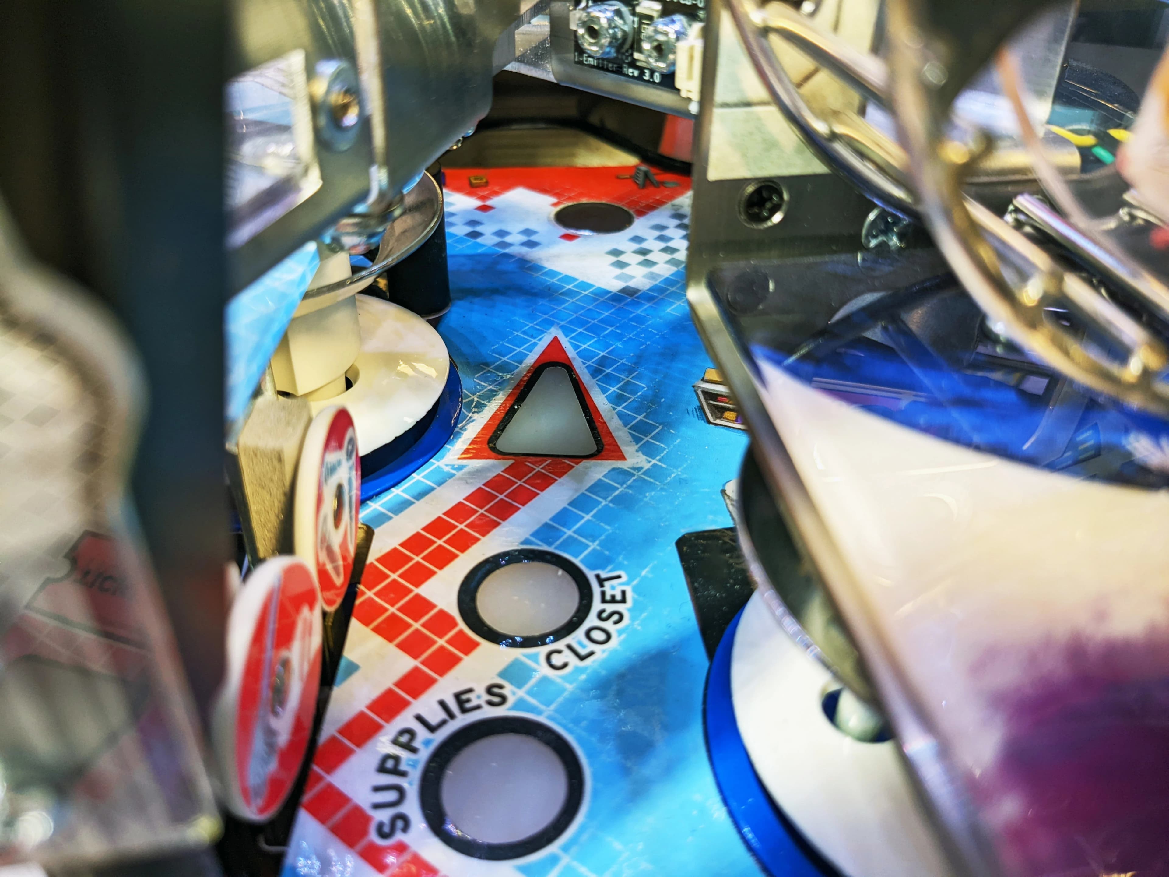 Close-up of a pinball machine playfield with colorful grid design