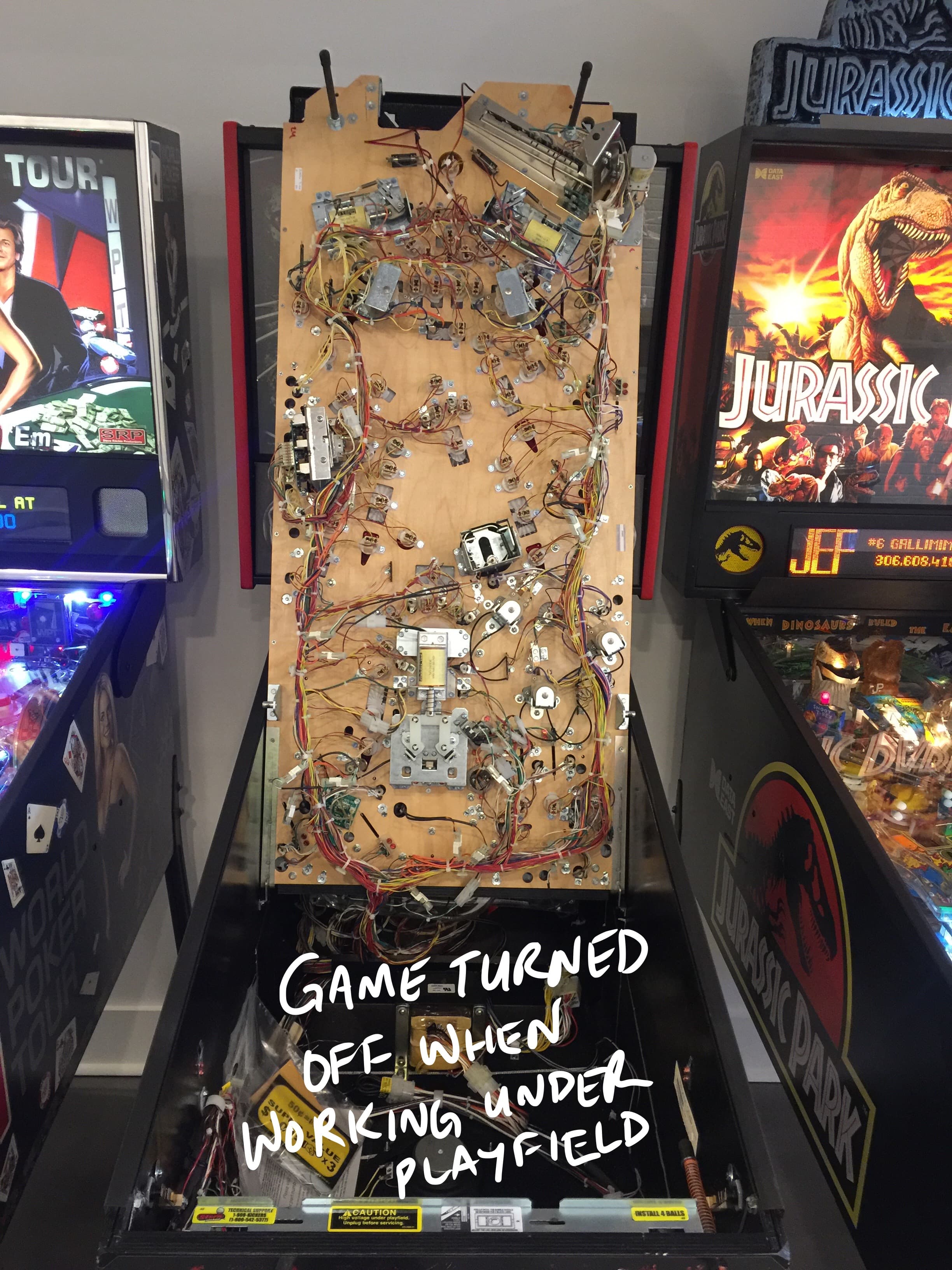 Exposed pinball machine interior with complex wiring and circuit board