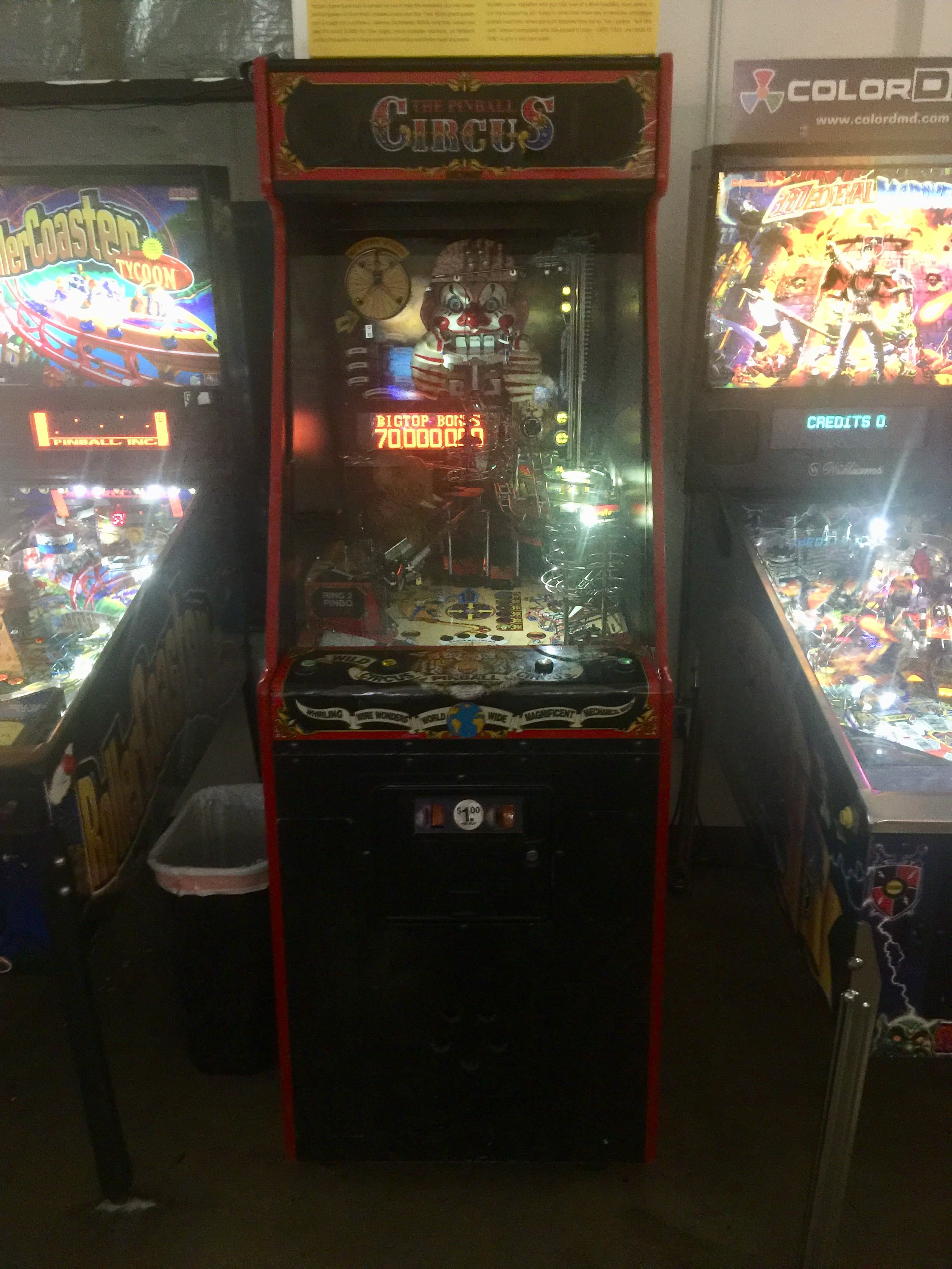 Vintage circus-themed pinball machine with creepy clown in arcade