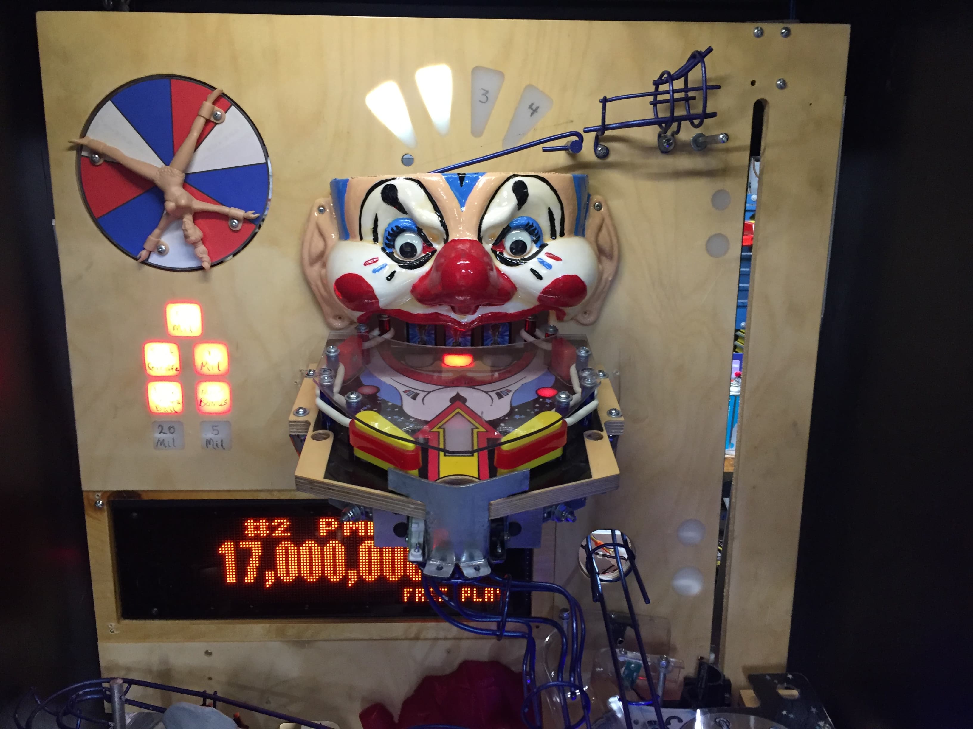 Creepy clown-faced pinball machine with digital scoreboard and colorful lights