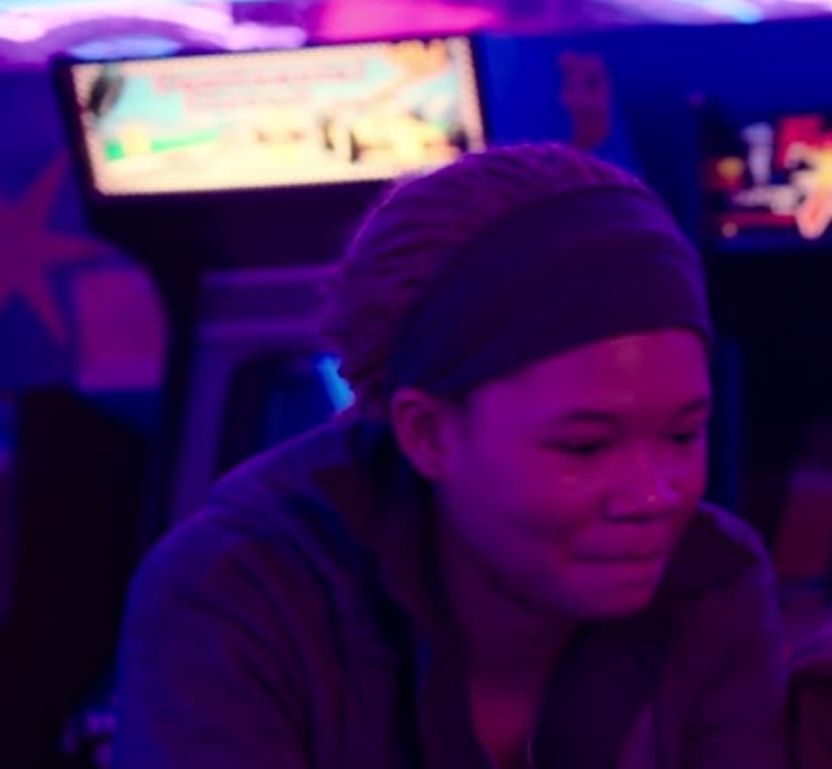 Person looking down in neon-lit room with screen in background
