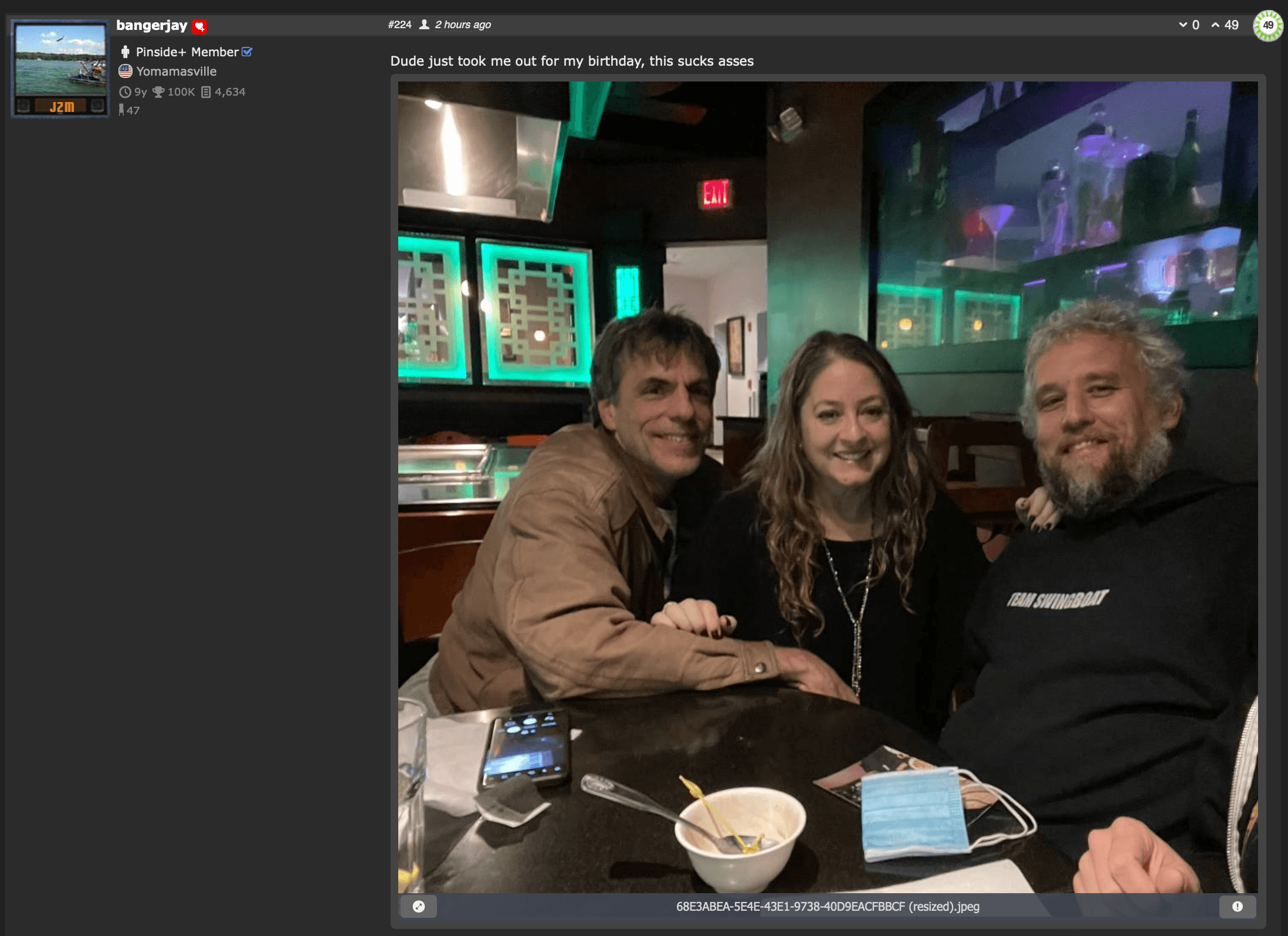 Three friends sitting at a table in a green-lit restaurant or bar