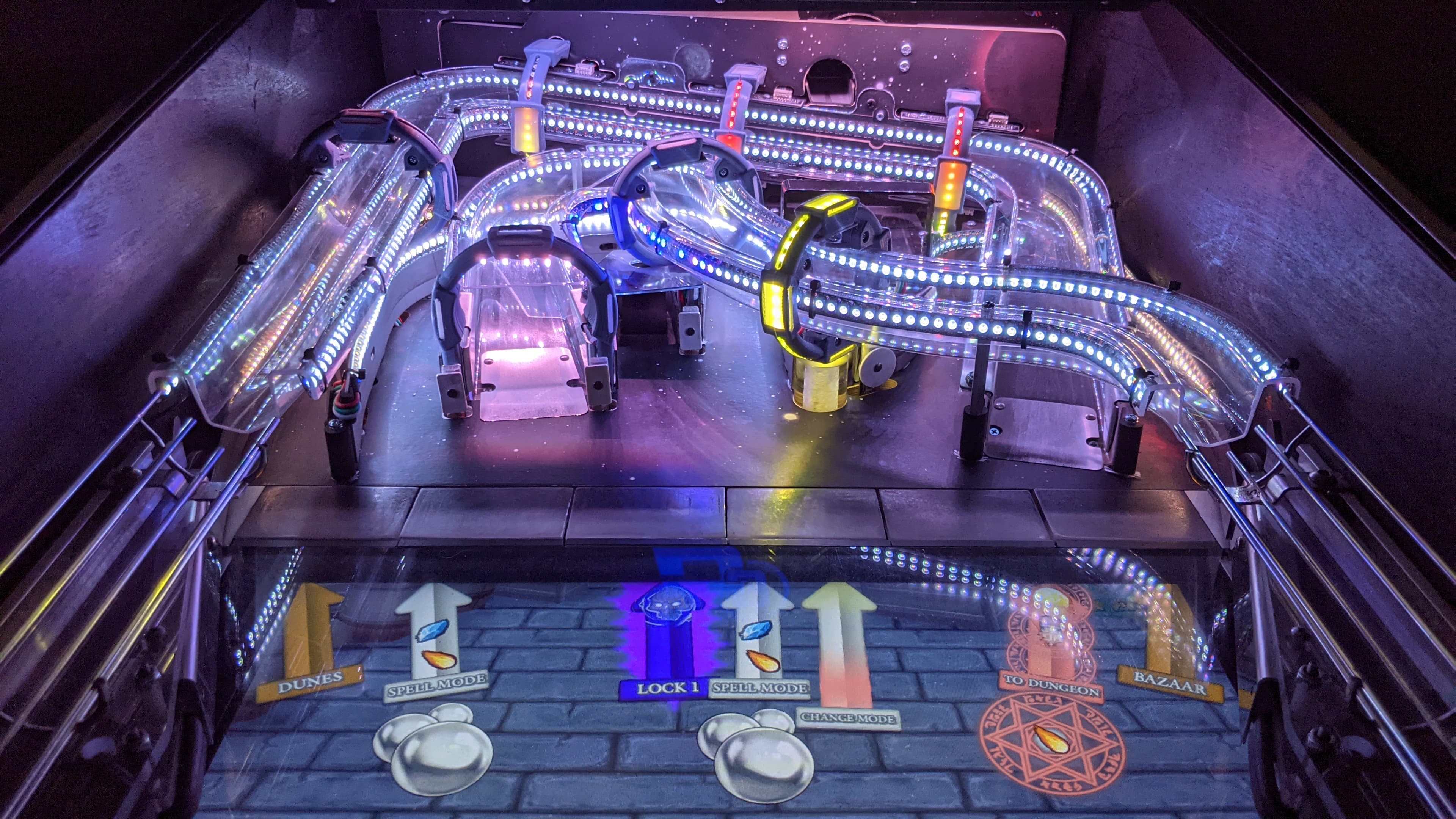 Illuminated pinball machine with intricate LED-lit tracks and magical fantasy design